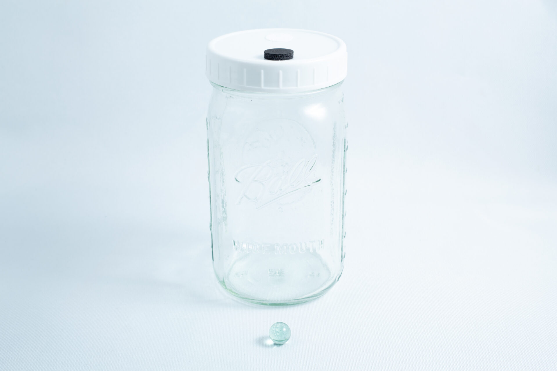 Mycology Ball mason jar with injection port and air vent 1L genuine autoclavable 5 A Mycology Ball Kilner jar with injection port and air vent, 1L genuine and autoclavable, sits next to a small glass marble on a white background.
