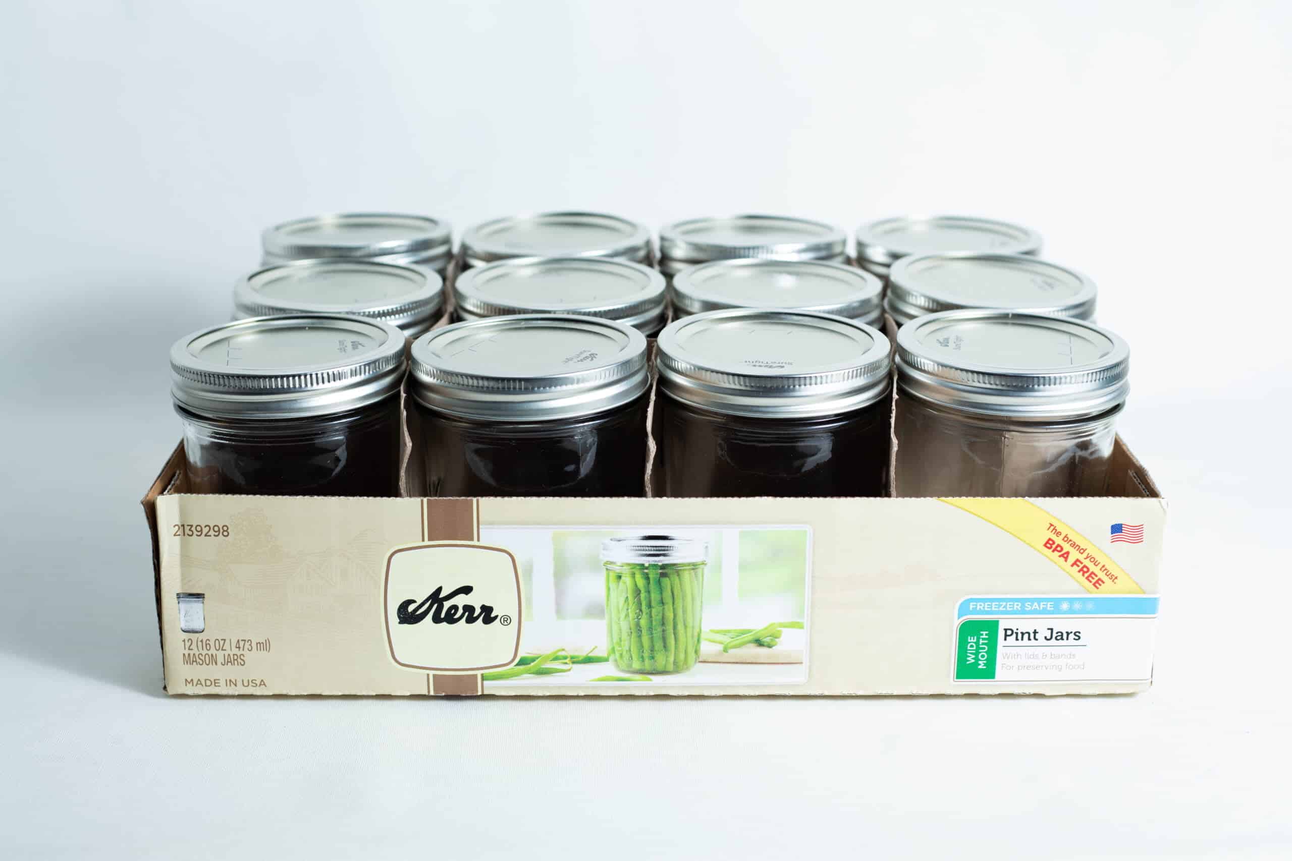 Kerr wide mouth Mason jar glass pint size 473ml with lids and bands x 12 1 A box of twelve Kerr wide mouth Mason jars, each 473ml pint size with lids and bands, neatly arranged in three rows.