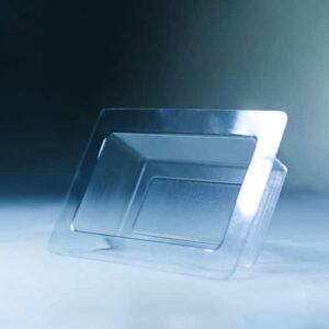 A Mycelium Mould Growth form -Brick (Reusable) stands upright on a smooth, misty surface, its organic curves reflected in the transparent plastic food container lid beside it.