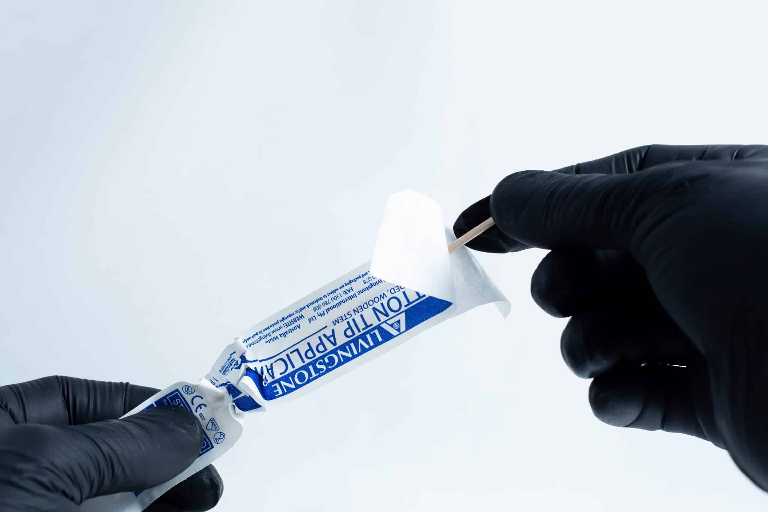 Agar petri dish MEA School Science Fun Project Kit 2 Gloved hands opening a blue antiseptic towelette packet with a cotton bud and the Agar petri dish MEA School Science Fun Project Kit nearby, set on a white background—ideal for school science experiments.