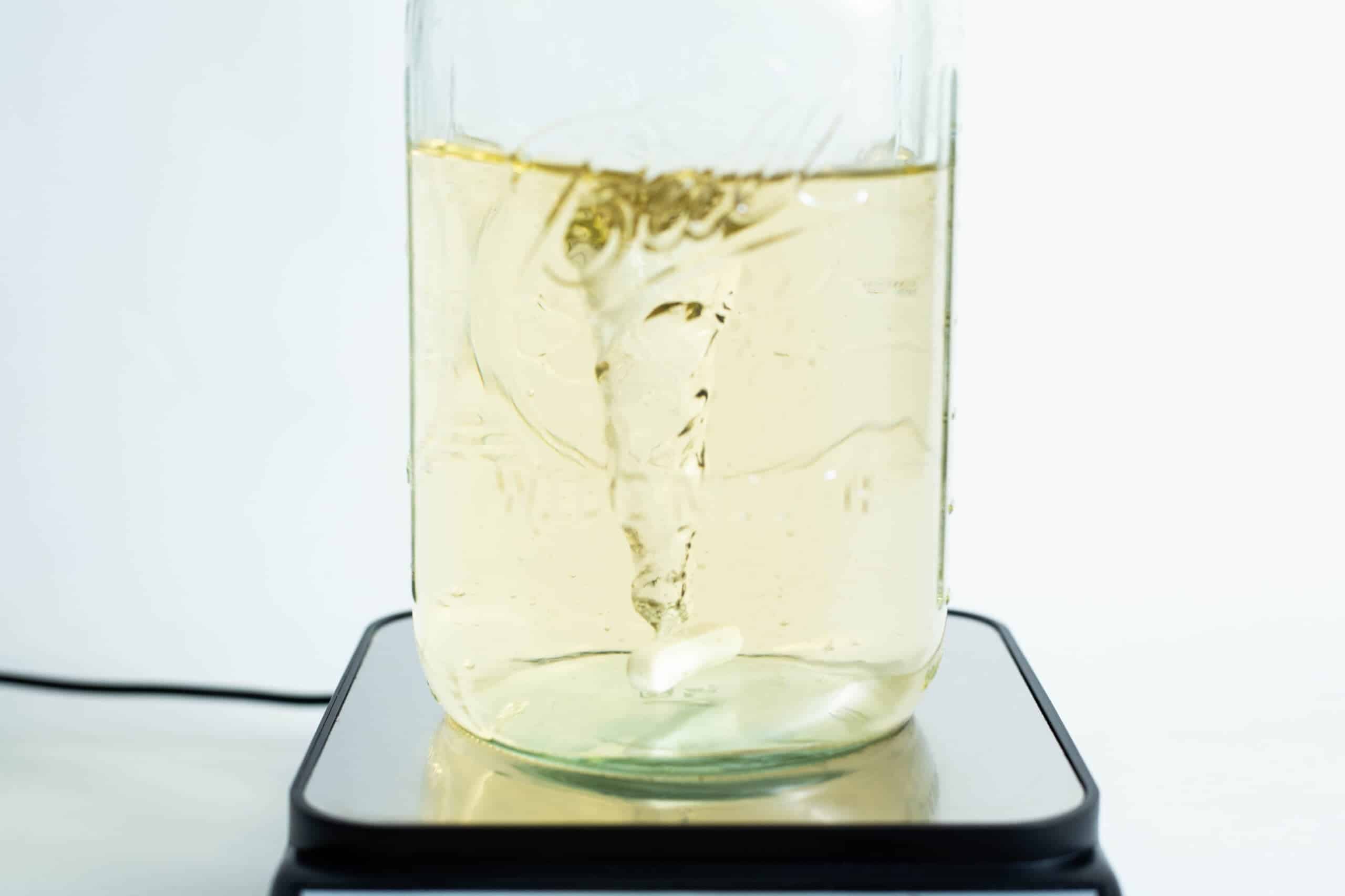 Magnetic Stirrer Ciblanc 3500rpm 5 A vortex swirls in a yellow liquid within a glass jar on the Magnetic Stirrer Ciblanc 3500rpm, highlighting the stirring precision of this device.
