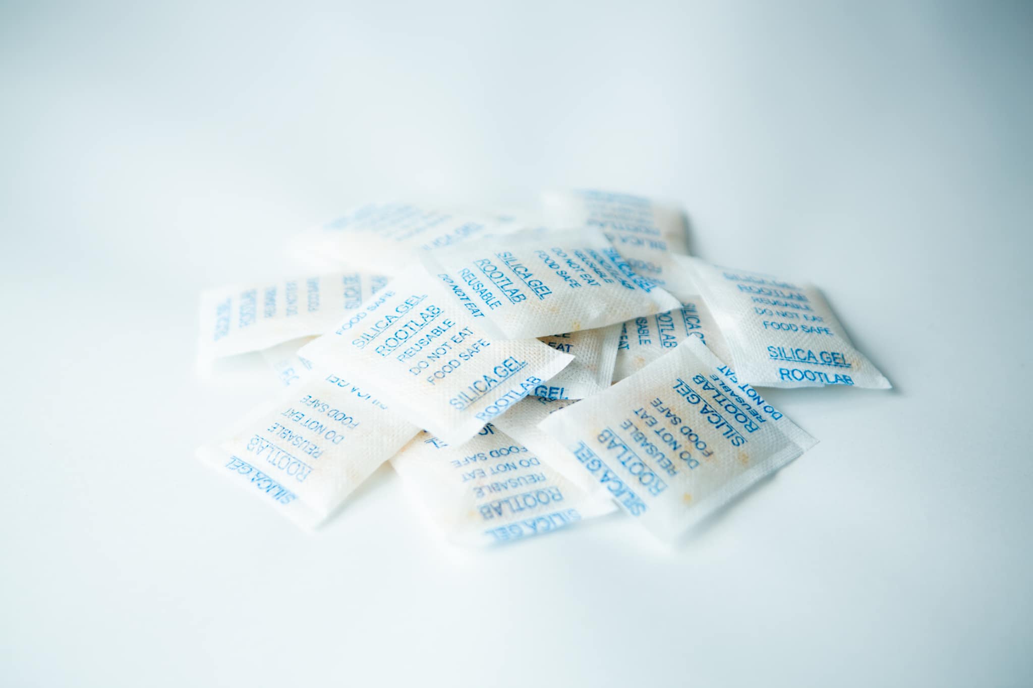Desiccant Silica Gel 5gm | Reusable 2 Desiccant Silica Gel 5g | Reusable sachets with blue writing are arranged on a white surface.
