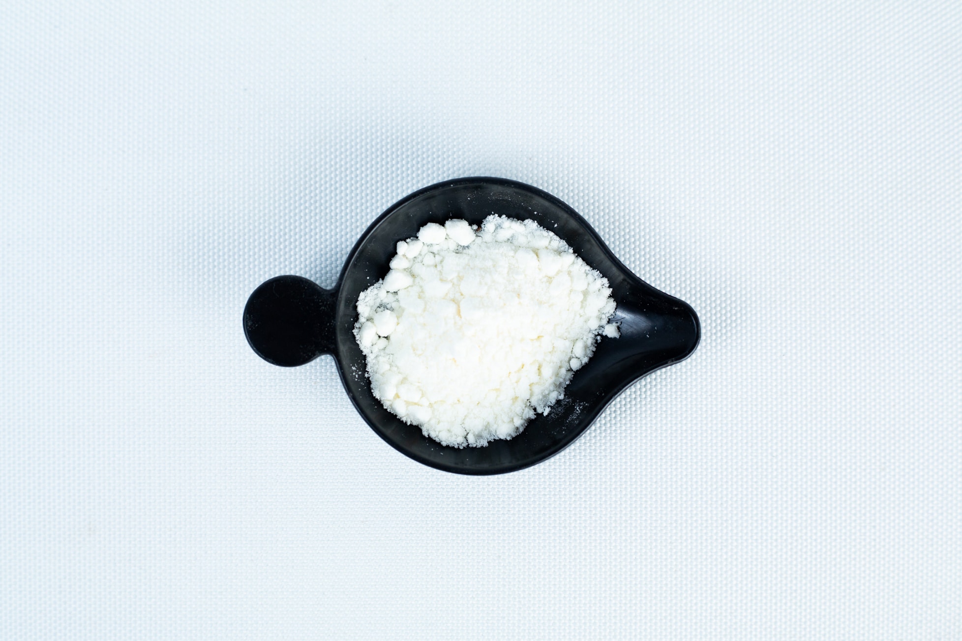 Antibacterial Powder for mushroom cultivation 2 A black bowl containing Antibacterial Powder for mushroom cultivation sits on a white textured surface.