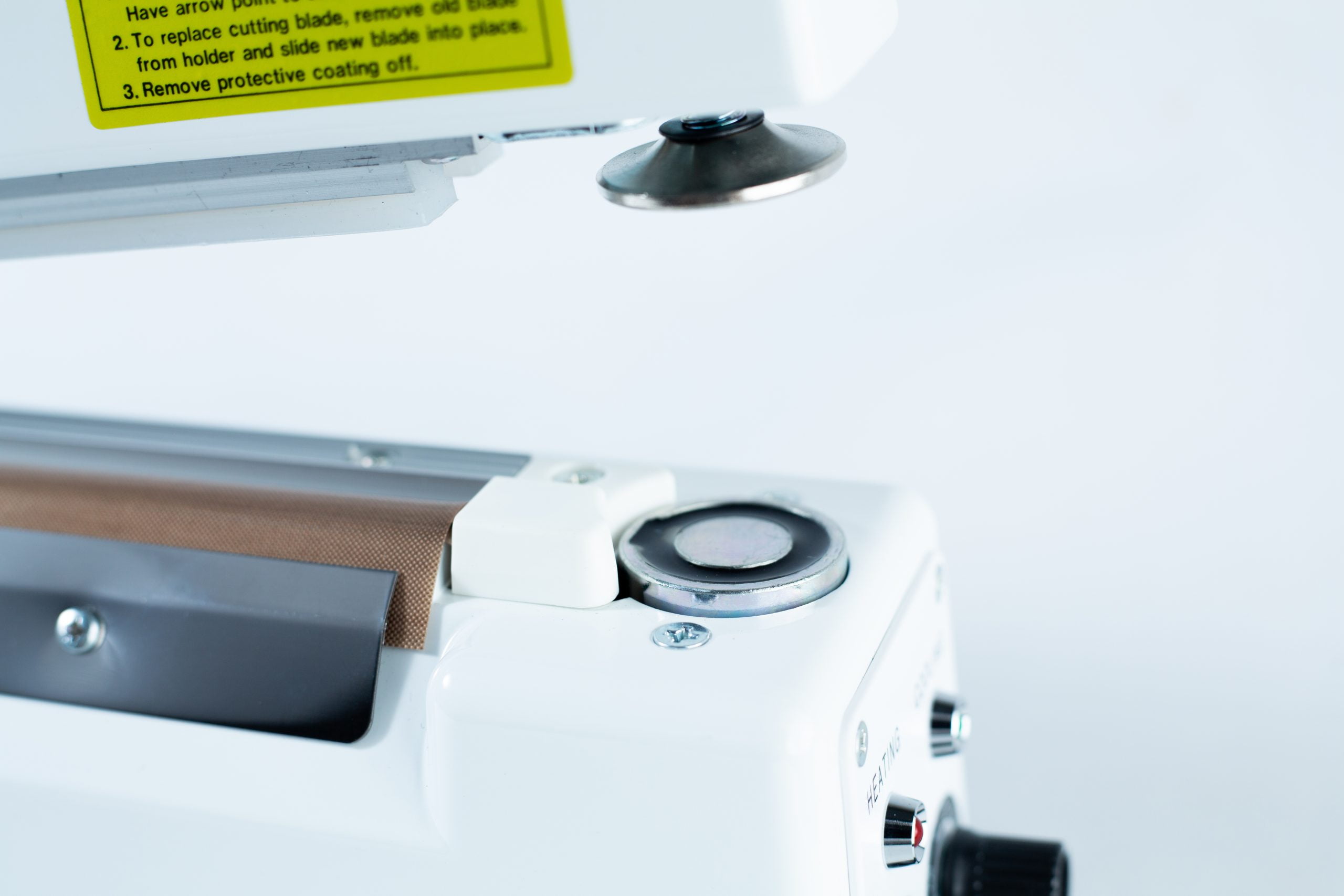 Heat Sealer 30cm Seal Width 5mm with cutter and Magnet 2 Close-up of the Heat Sealer 30cm Seal Width 5mm with cutter and magnet, highlighting its metal and plastic parts against a plain background.