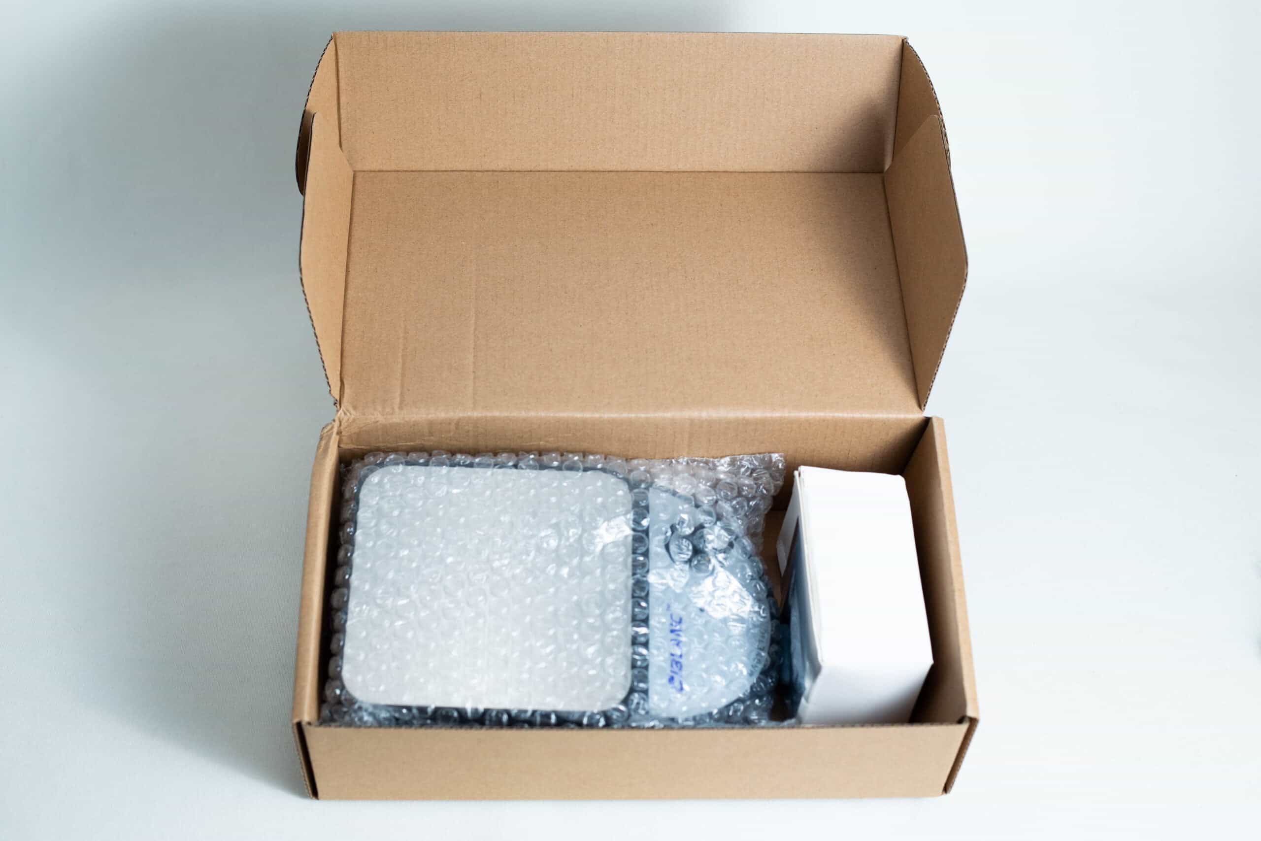 Magnetic Stirrer Ciblanc 3500rpm 4 Open cardboard box with bubble-wrapped items and a white rectangular box inside, possibly containing the Magnetic Stirrer Ciblanc 3500rpm—ideal for anyone seeking magnetic stirrer equipment. All items are neatly arranged on a white surface.