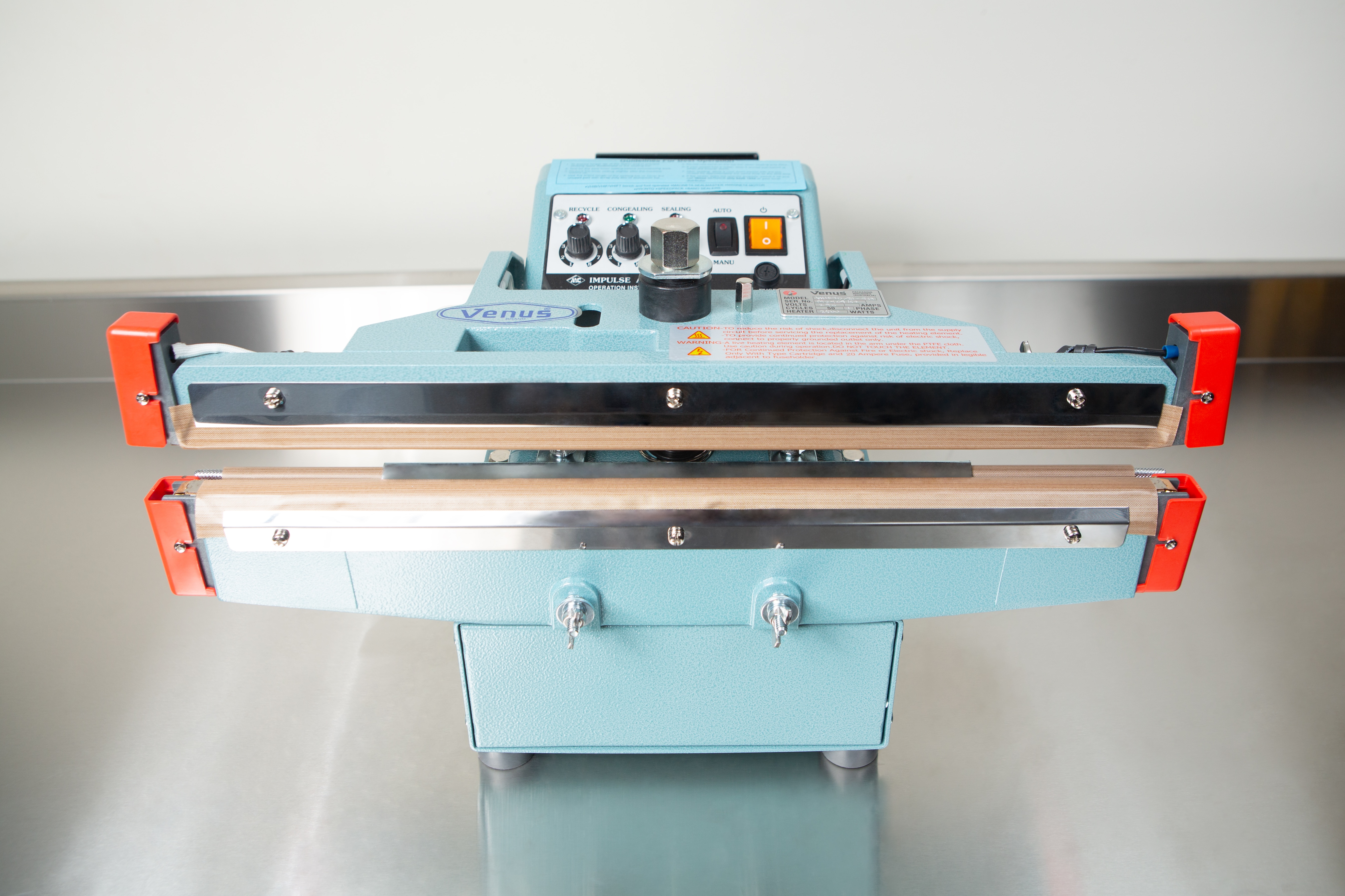 Heat Sealer 450mm with 10mm Seal | Benchtop Model 2 The Heat Sealer 450mm with 10mm Seal | Benchtop Model features a blue body, control panel, and orange clamps on a metal surface, offering efficient industrial sealing with its 450mm heat sealer.