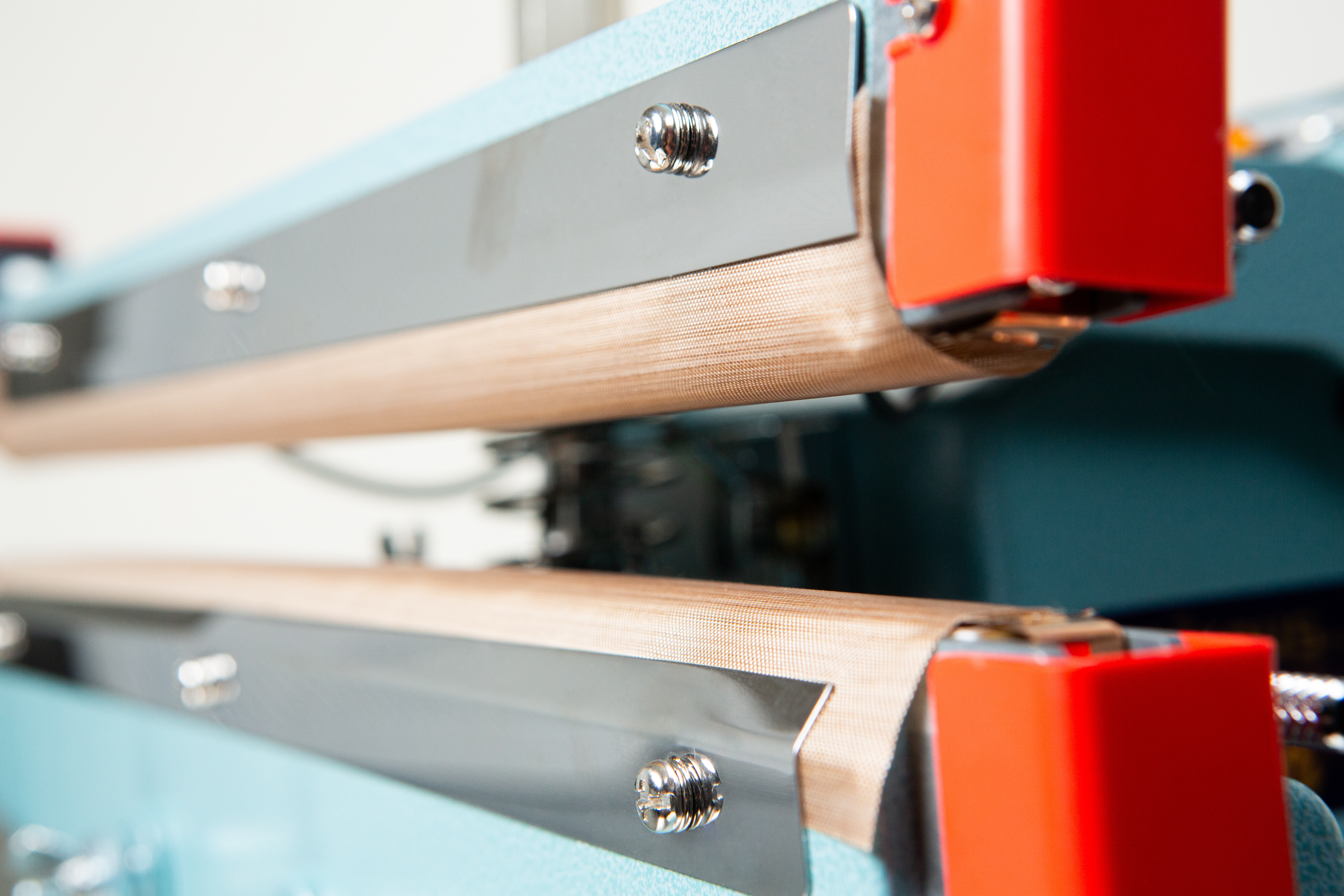Heat Sealer 450mm with 10mm Seal | Benchtop Model 4 Close-up view of industrial machine parts with metal bars and red components, featuring the Heat Sealer 450mm with 10mm Seal | Benchtop Model for efficient sealing operations.