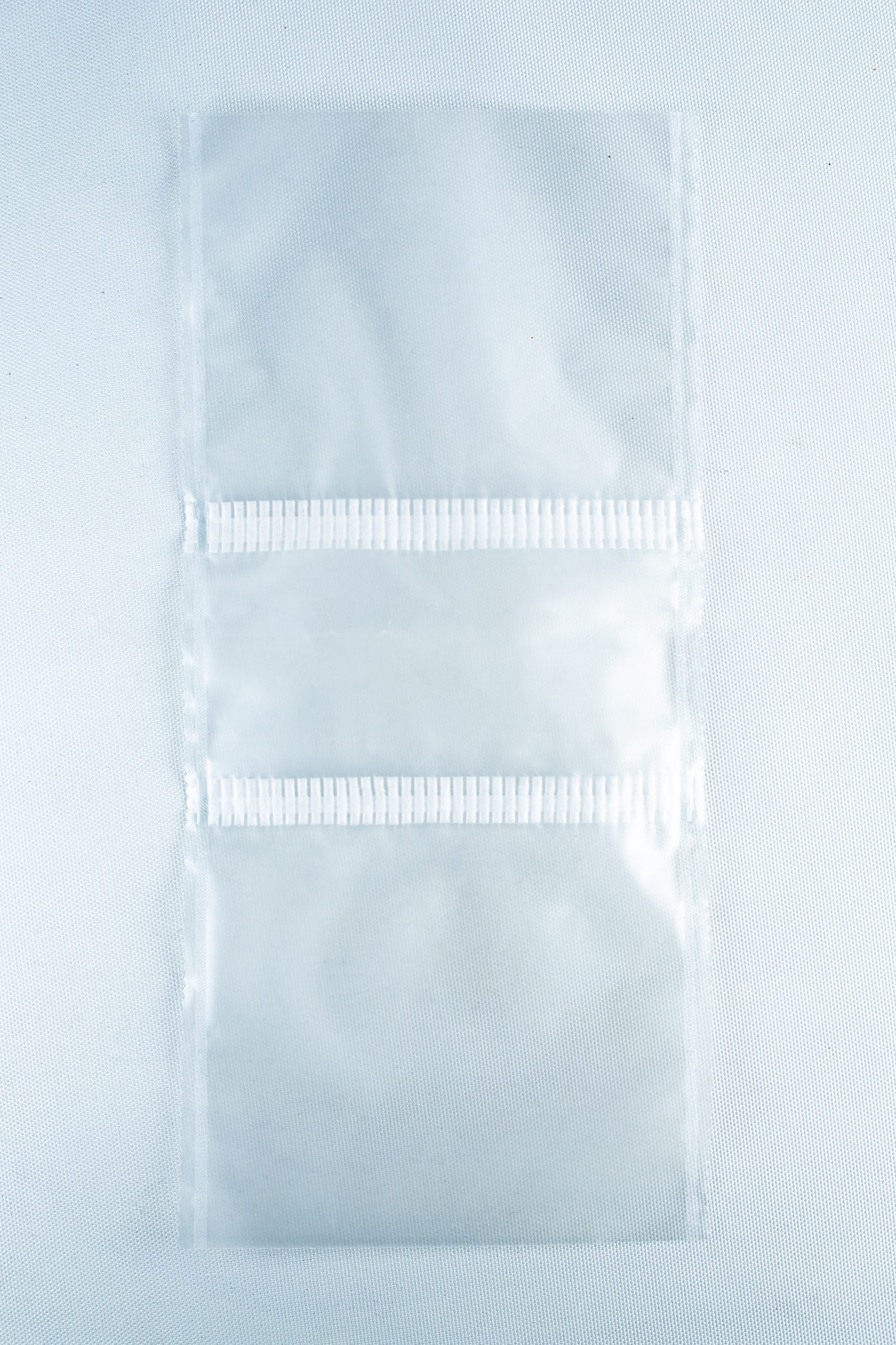 Grow bags Mushroom Sac O2 4 Two empty, clear Mushroom Grow Bags Unicorn for spawn and substrate are joined by a perforated line and placed on a plain white surface.