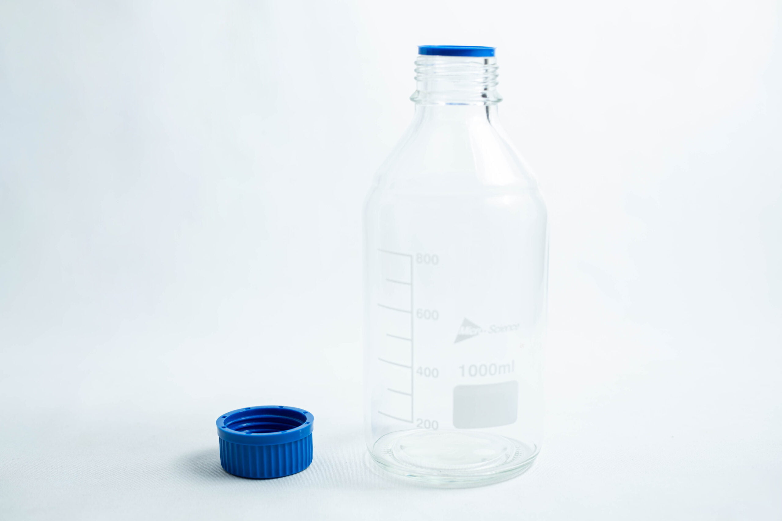 Reagent bottle 500ml / 1000ml 2 A clear reagent bottle 500ml / 1000ml with measurement lines and a blue cap beside it.