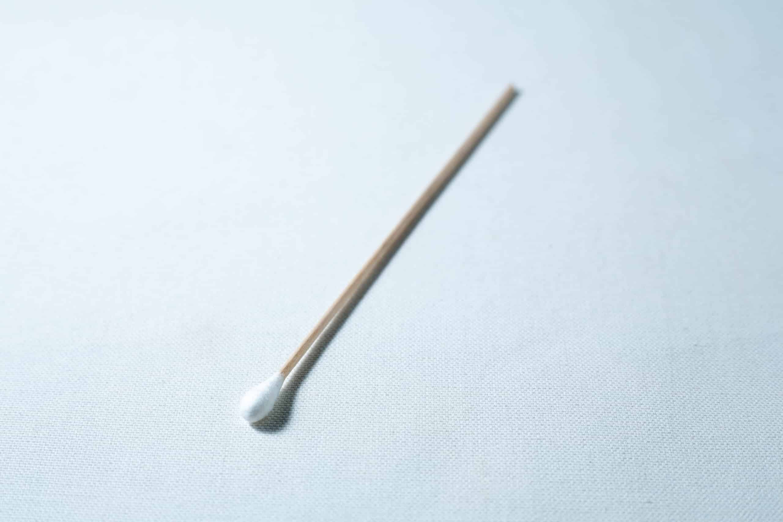 Sterile Cotton Tip Applicator/ Swab 2 A single sterile cotton wool bud with a wooden stick is placed on a white surface.