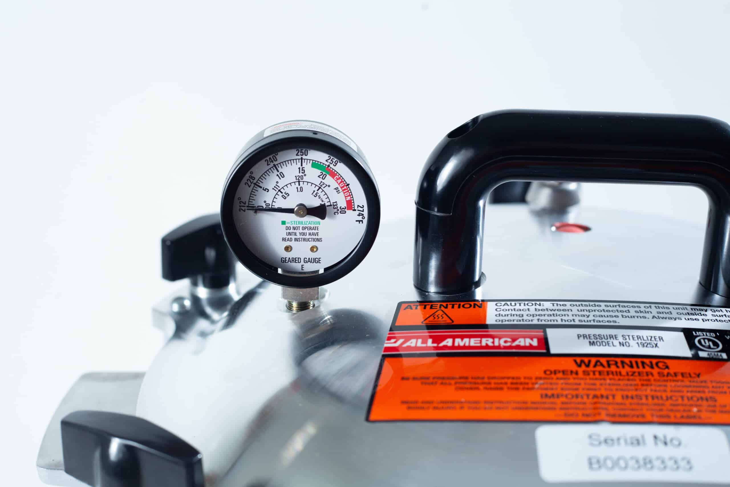 1925x All-American Sterilizer (Autoclave) 25 quart/ 24 Liter 7 Close-up of a pressure gauge and warning labels on a stainless steel pressure steriliser.