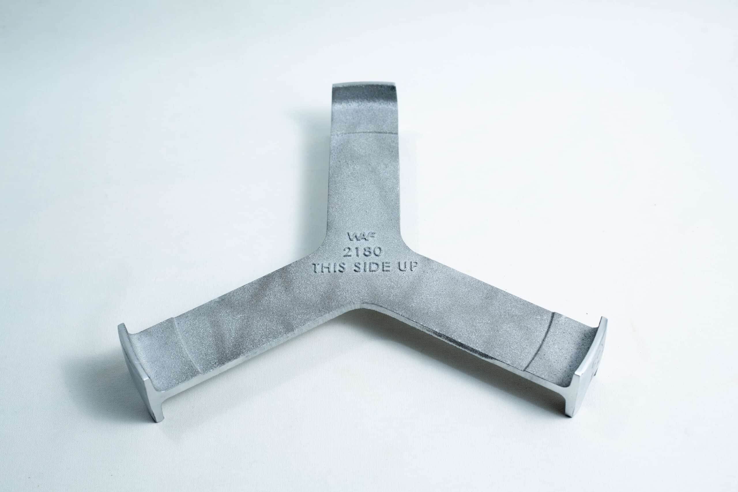 All American 2180 Support Base for 25X and 50X Sterilizers 1 Grey metal object with three prongs and “THIS SIDE UP” engraved at the centre, placed on a white surface.