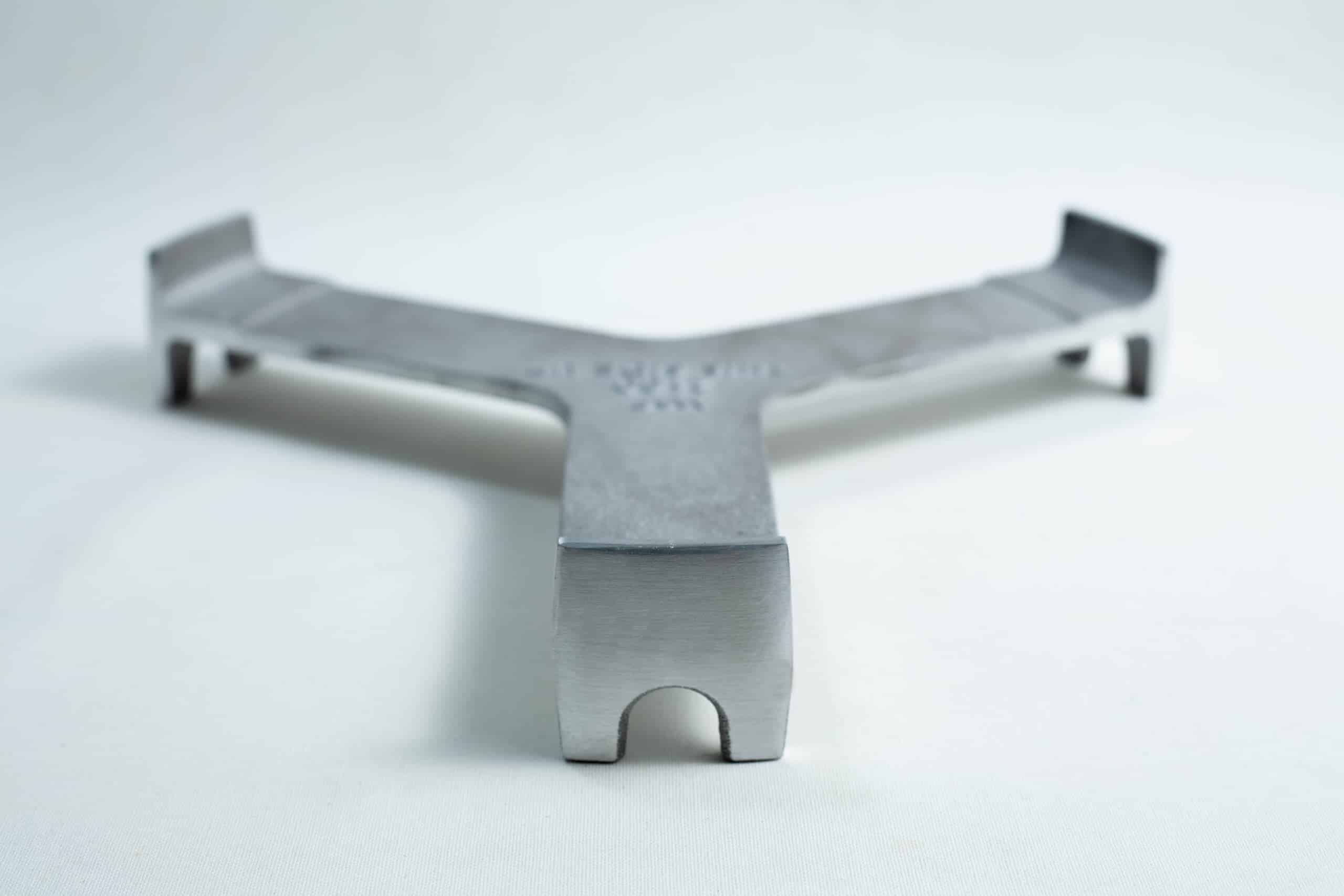 All American 2180 Support Base for 25X and 50X Sterilizers 2 A metal trivet with three arms rests on a white surface, viewed from a low front angle.