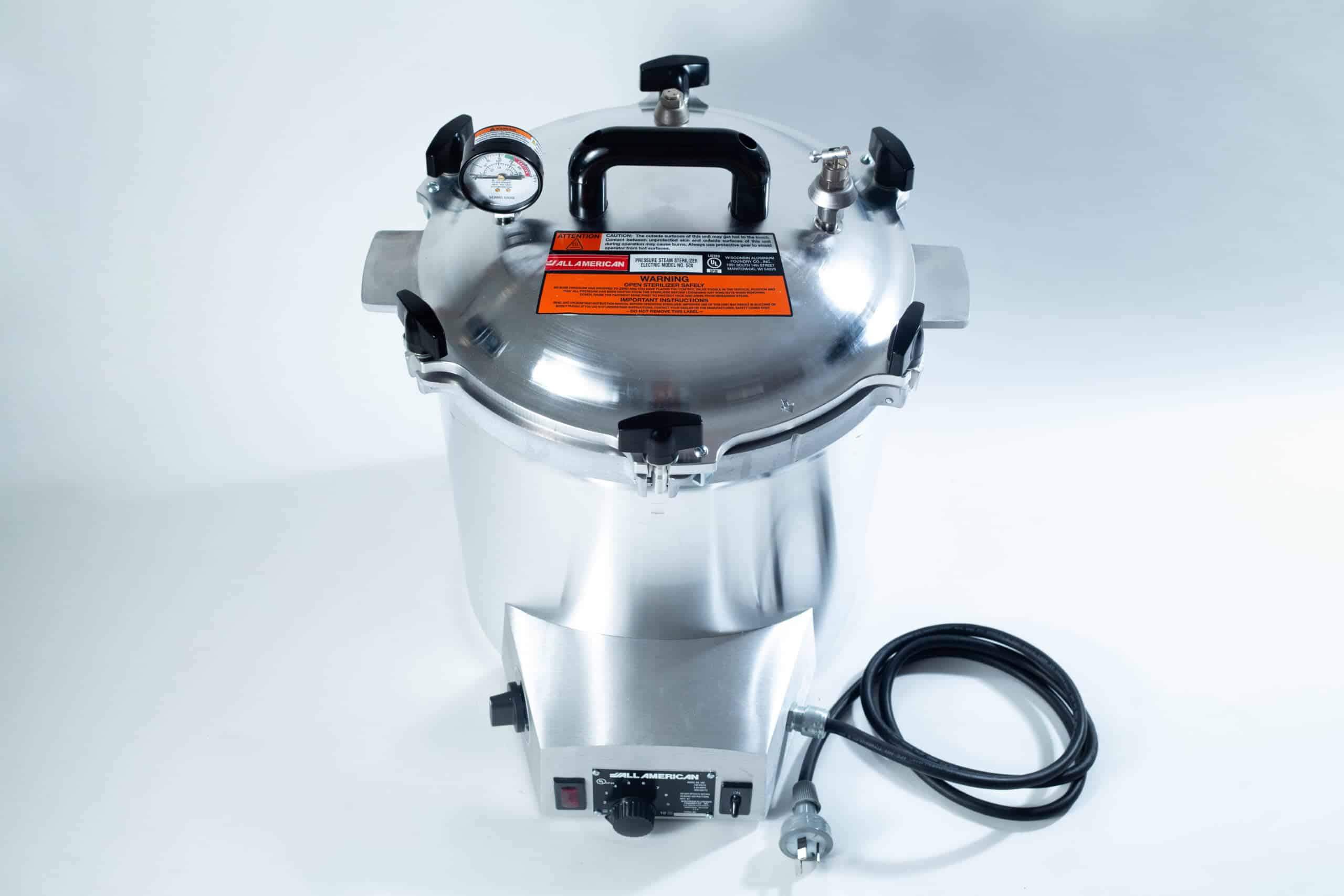 50x All American electric autoclave sterilizer 25 quart 2 A stainless steel pressure cooker with a gauge, black handles, and an attached power lead on a white background.