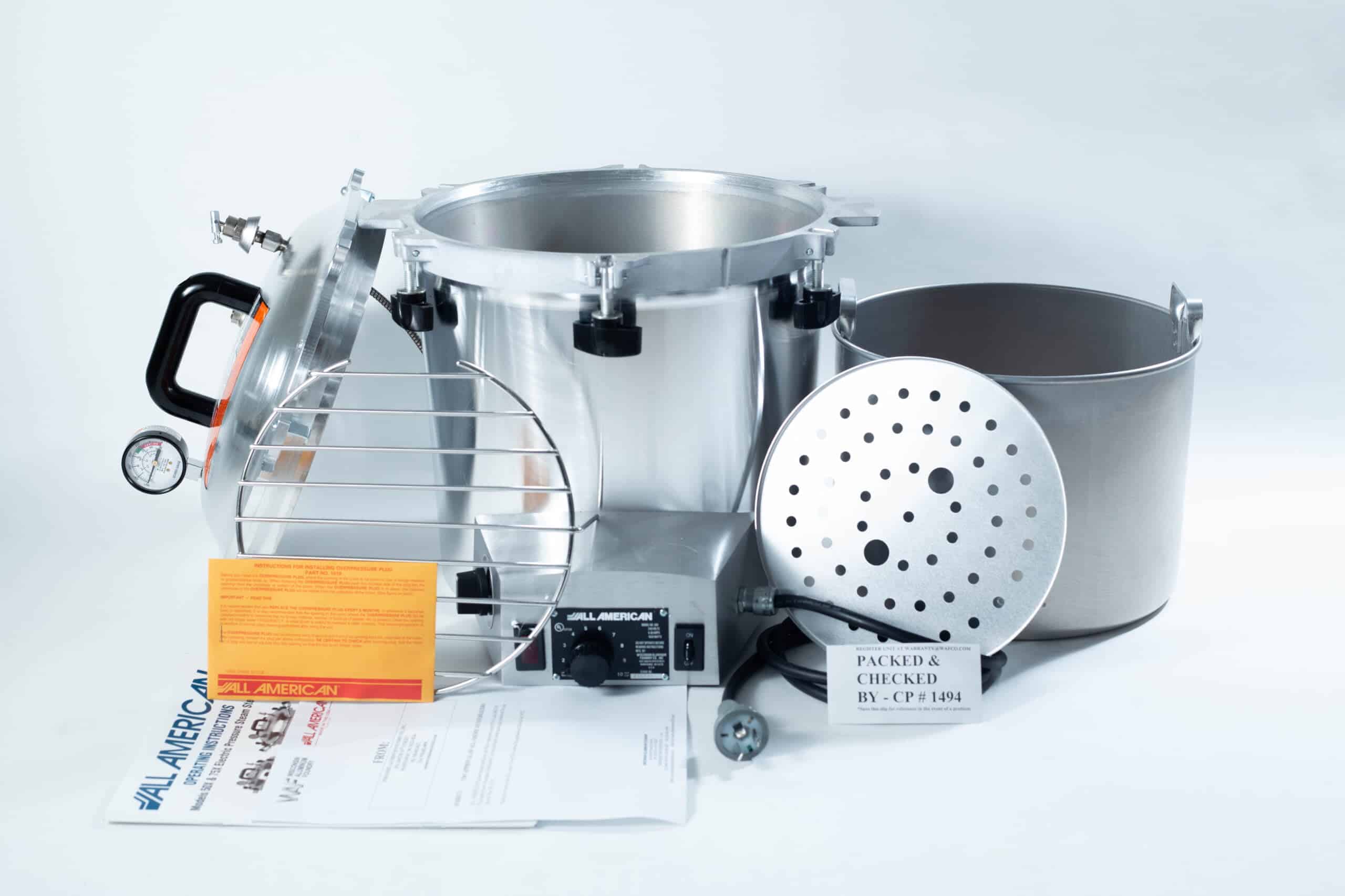 50x All American electric autoclave sterilizer 25 quart 4 Parts of a pressure canner, including pot, lid, racks, gauge, and instruction leaflets, arranged on a white background.