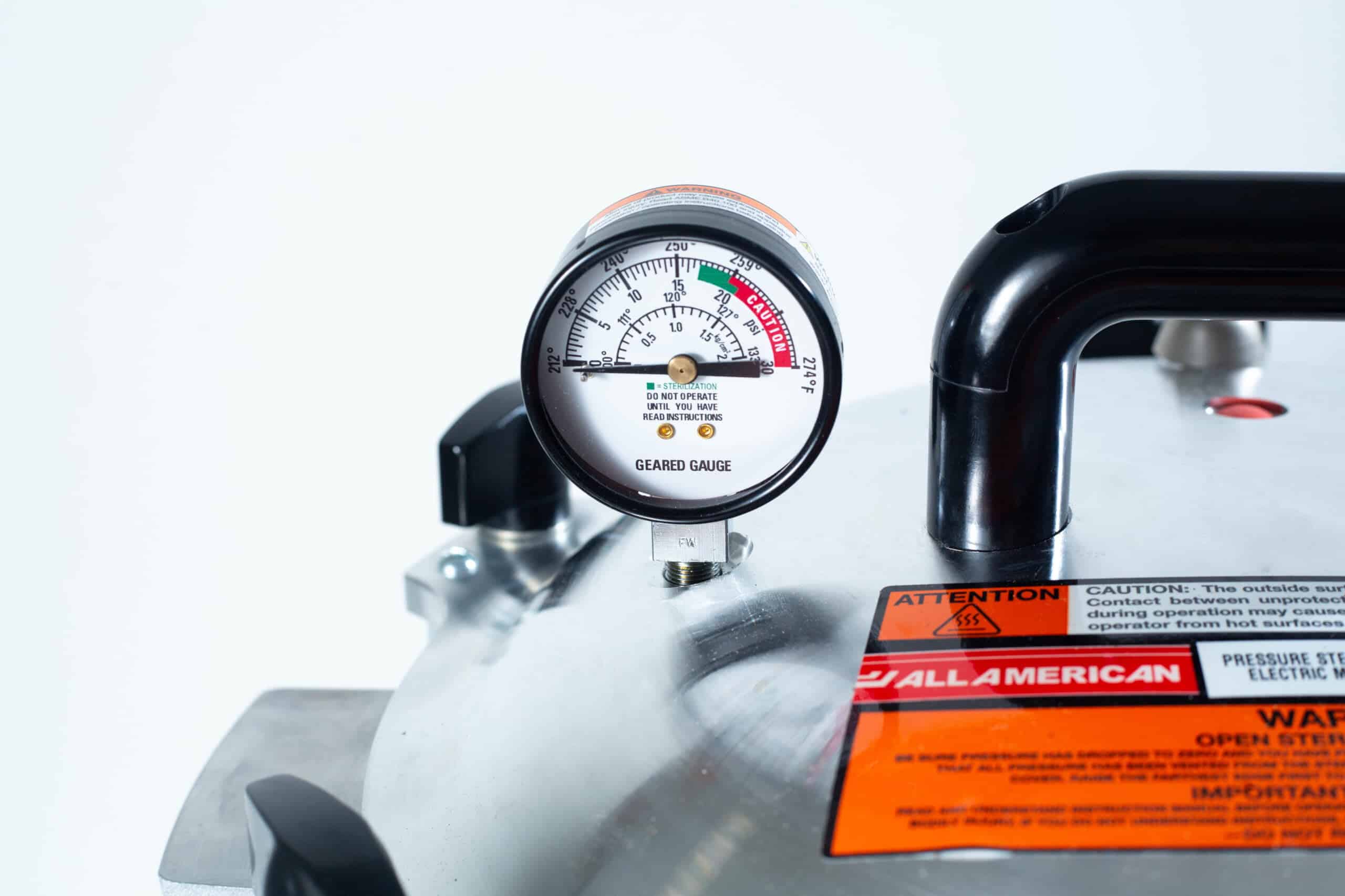50x All American electric autoclave sterilizer 25 quart 8 Close-up of a pressure gauge on a metal appliance with caution and warning labels visible.