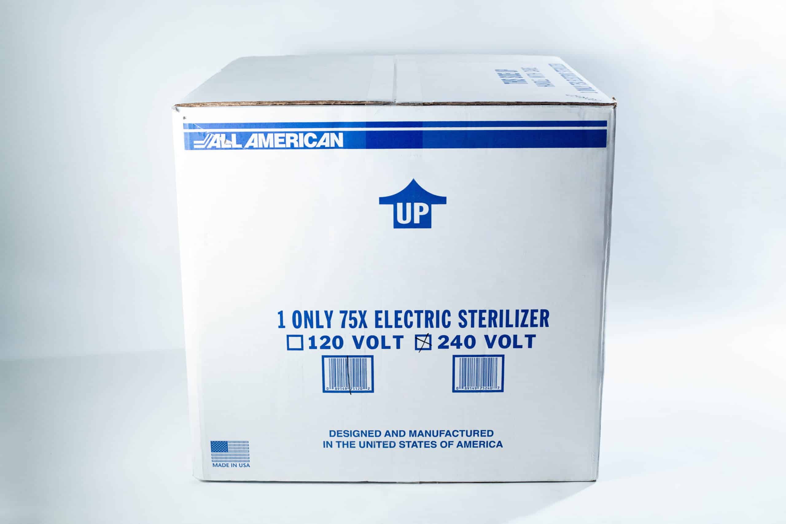 75x All American electric autoclave sterilizer 41 quart 10 A cardboard box labelled All American containing a 75X electric steriliser, marked UP with voltage options.