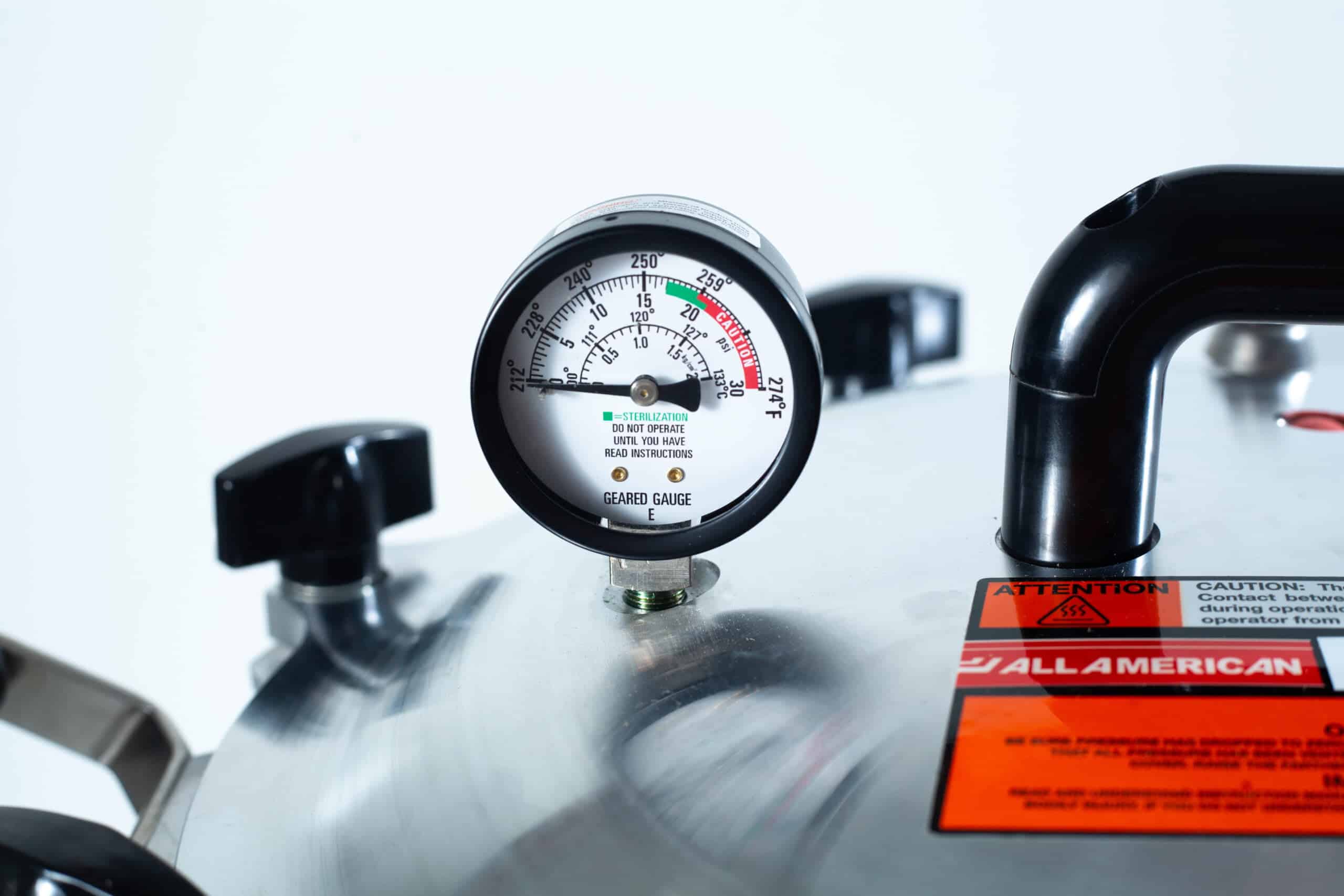 75x All American electric autoclave sterilizer 41 quart 8 Close-up of a pressure gauge on a metal pressure cooker with caution labels visible.
