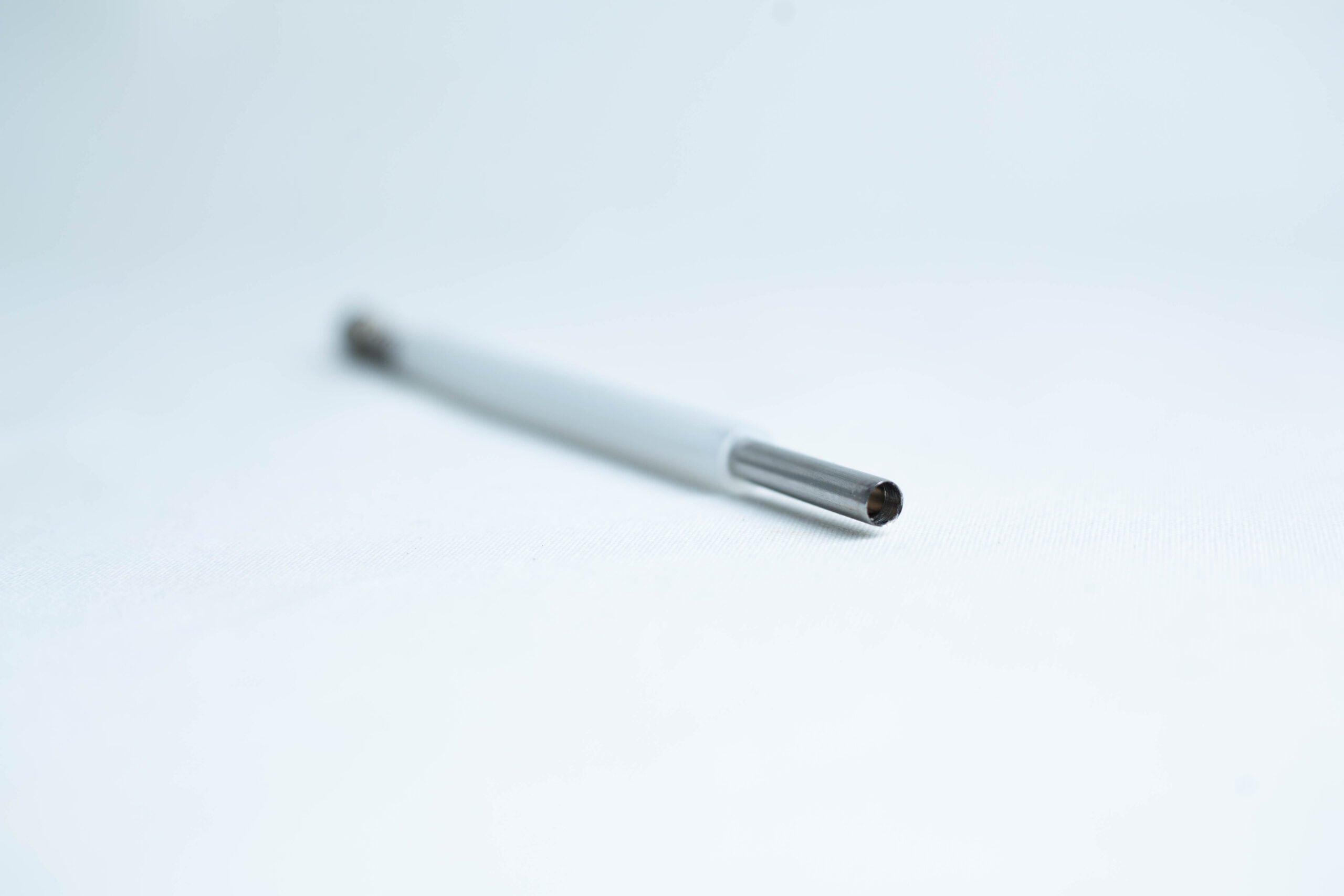 Agar punch transfer tool 3 A close-up of a pen refill lying on a white surface with a blurred background.