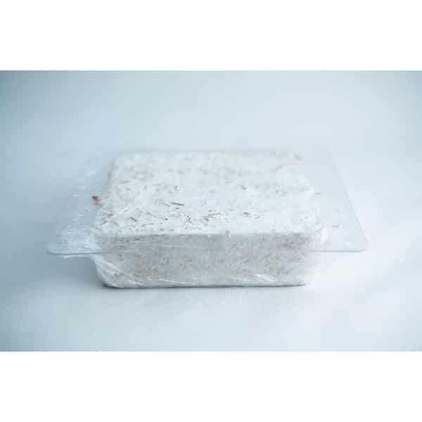 A block of white, shredded material in a clear plastic container on a light background.