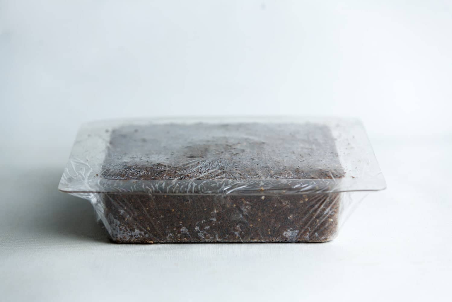 Mycelium Mold Growth form - Paver (Reusable) 9 A rectangular block of soil in a plastic container covered with clear plastic film.