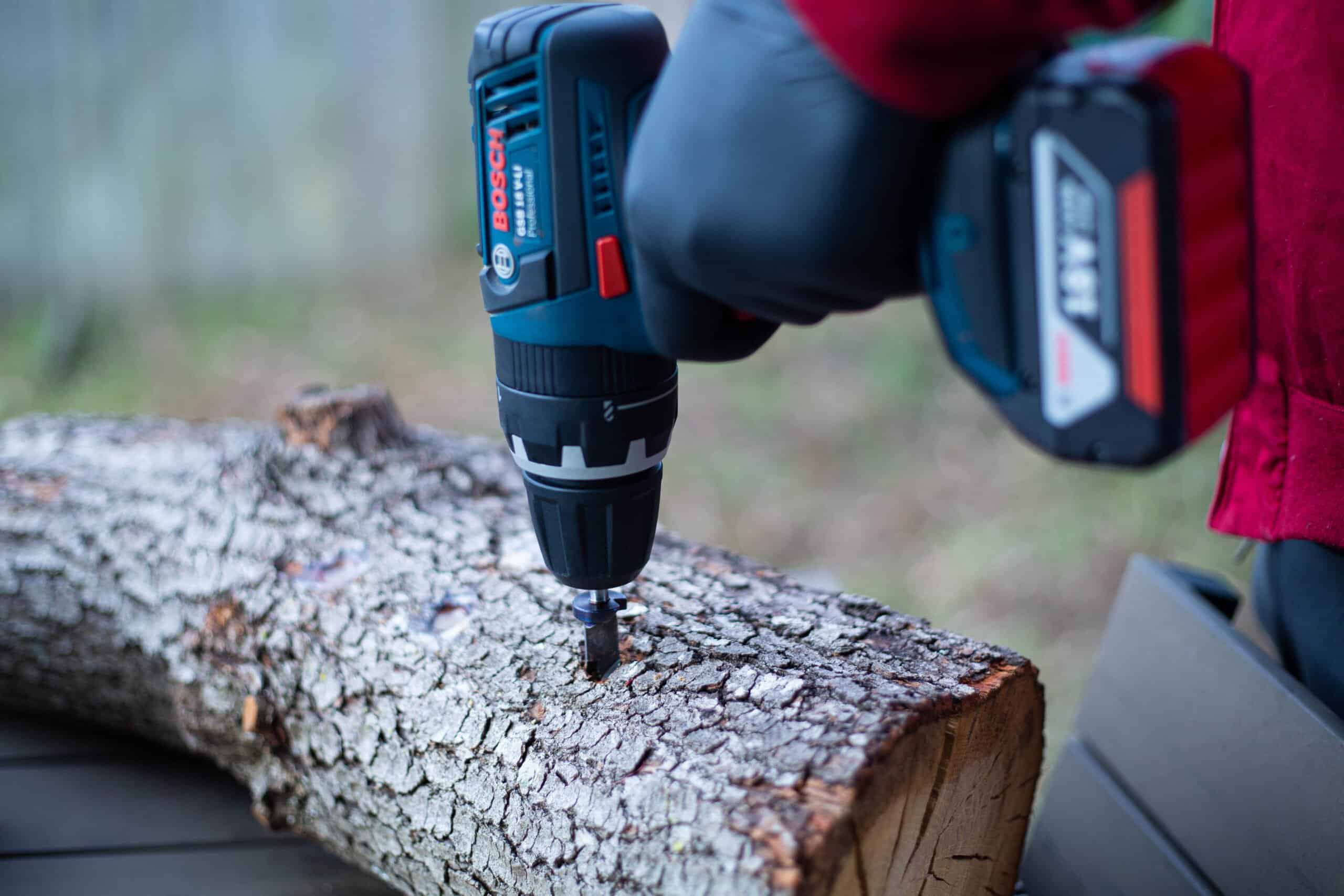 12.5 mm Sawdust Inoculation Drill Bit With Stopper, Hex Shank 5 A person drills into a tree log using a cordless power drill outdoors.