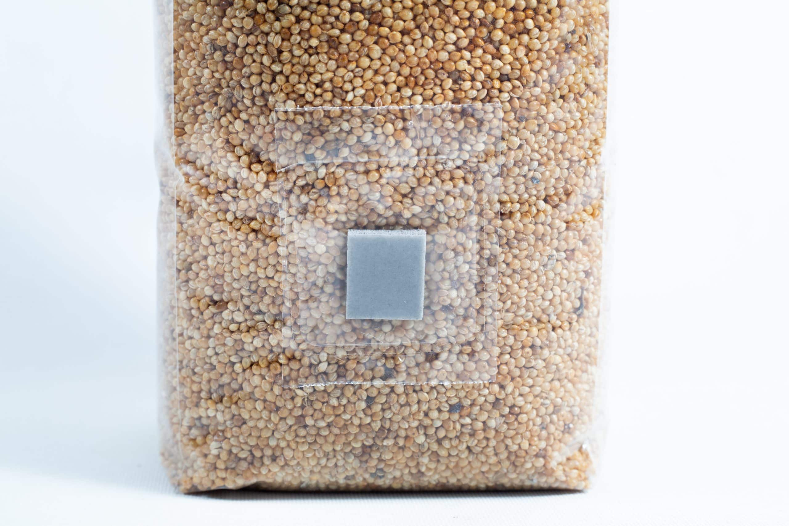 Millet pre sterilized mushroom grains w/inj port and digital instructions 7 A clear plastic bag of millet pre-sterilised mushroom grains with injection port and digital instructions, sealed with a grey square label.