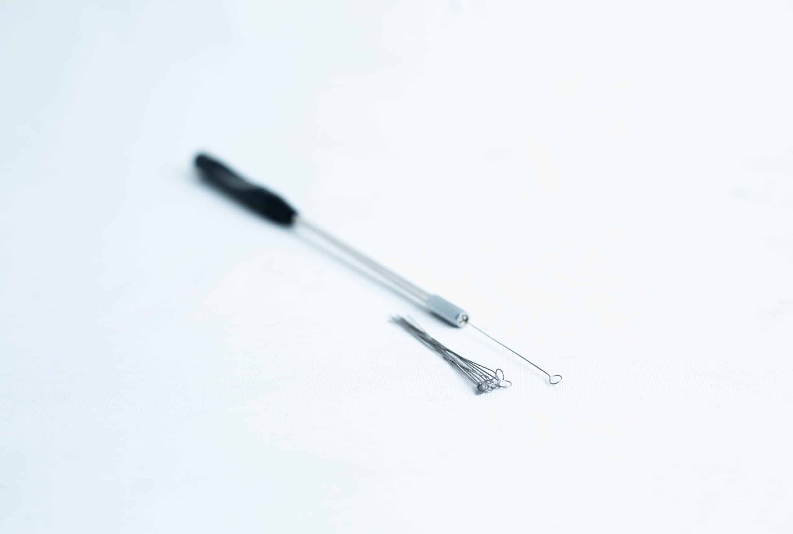 Inoculation Rod with Loops 2 Close-up of a metal inoculating loop tool and spare loops on a white surface.
