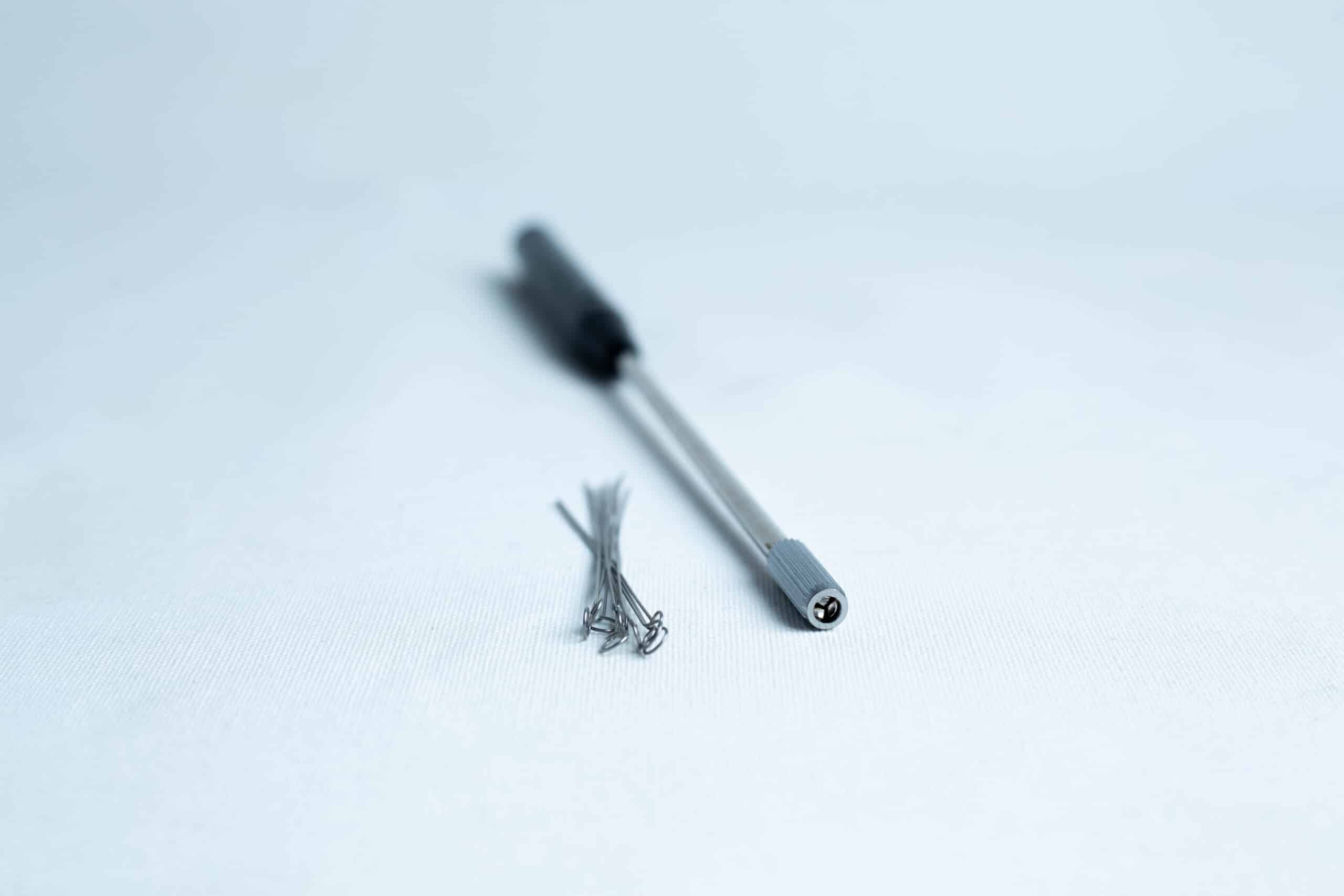 Inoculation Rod with Loops 1 A precision screwdriver and several small screws on a white surface.