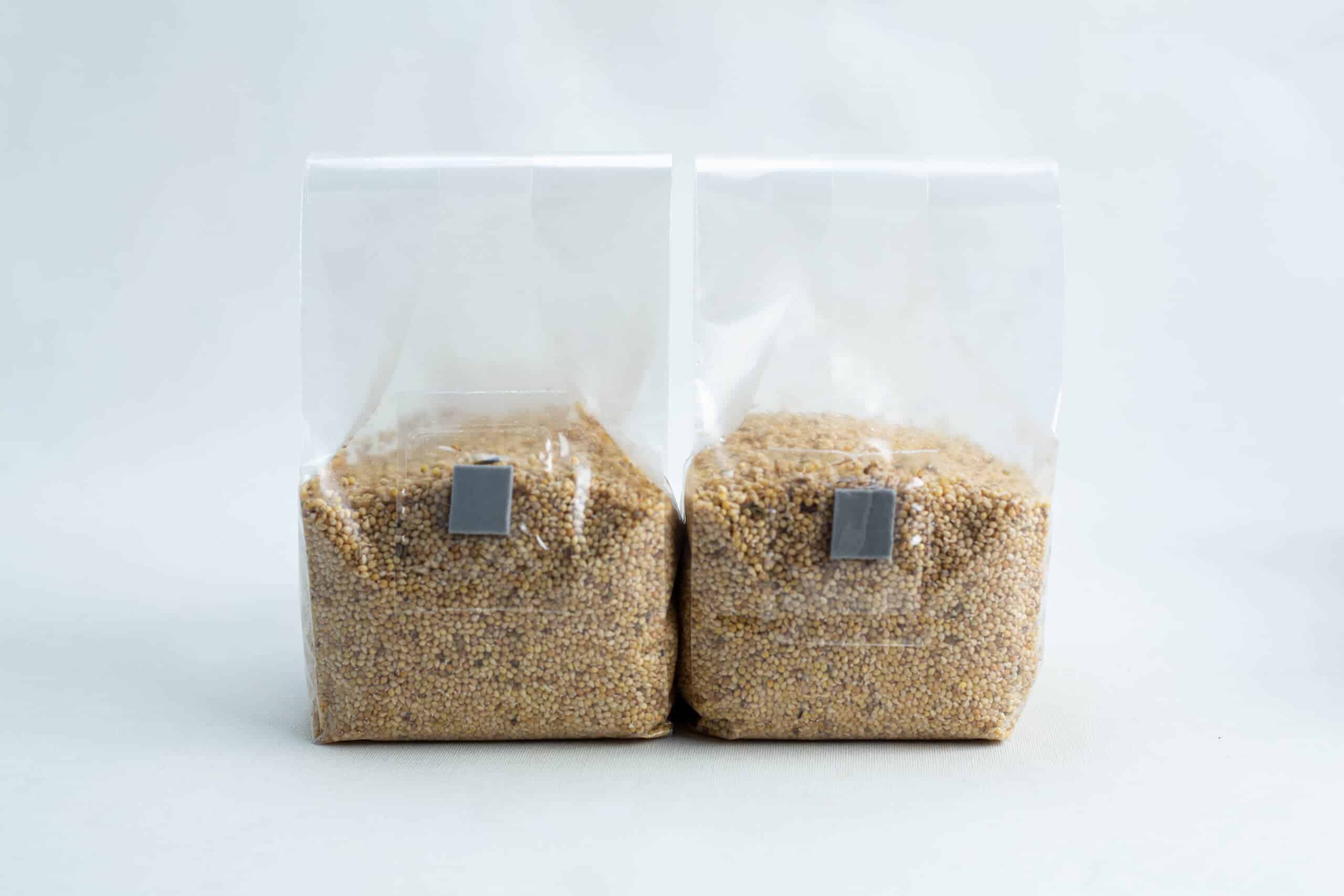 Millet pre sterilized mushroom grains w/inj port and digital instructions 3 Two clear plastic bags filled with grains, standing side by side on a white background.