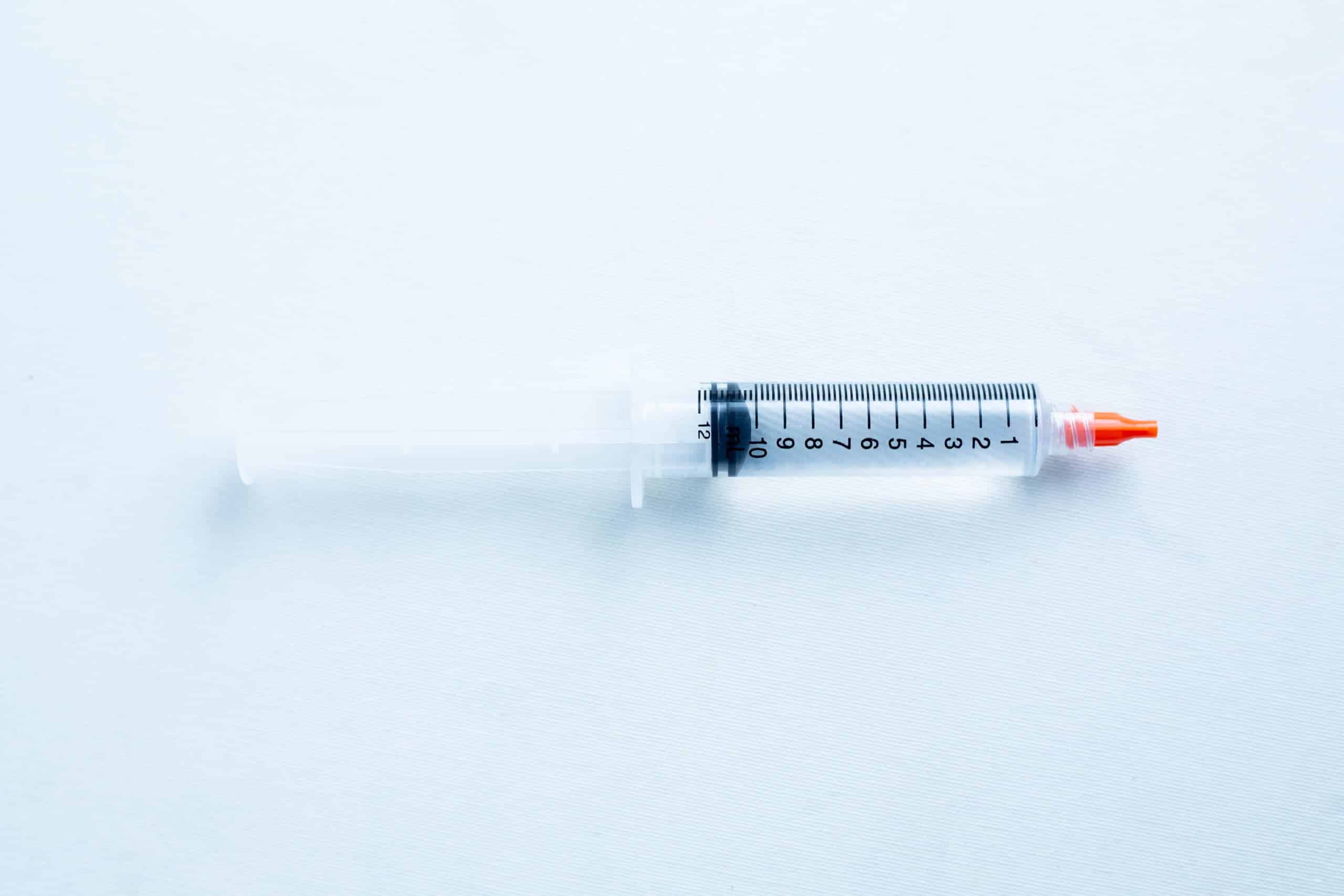Antibacterial sterile water or sterile water to make spore syringe 2 A plastic syringe with a red cap and black measurement markings lies on a white surface.