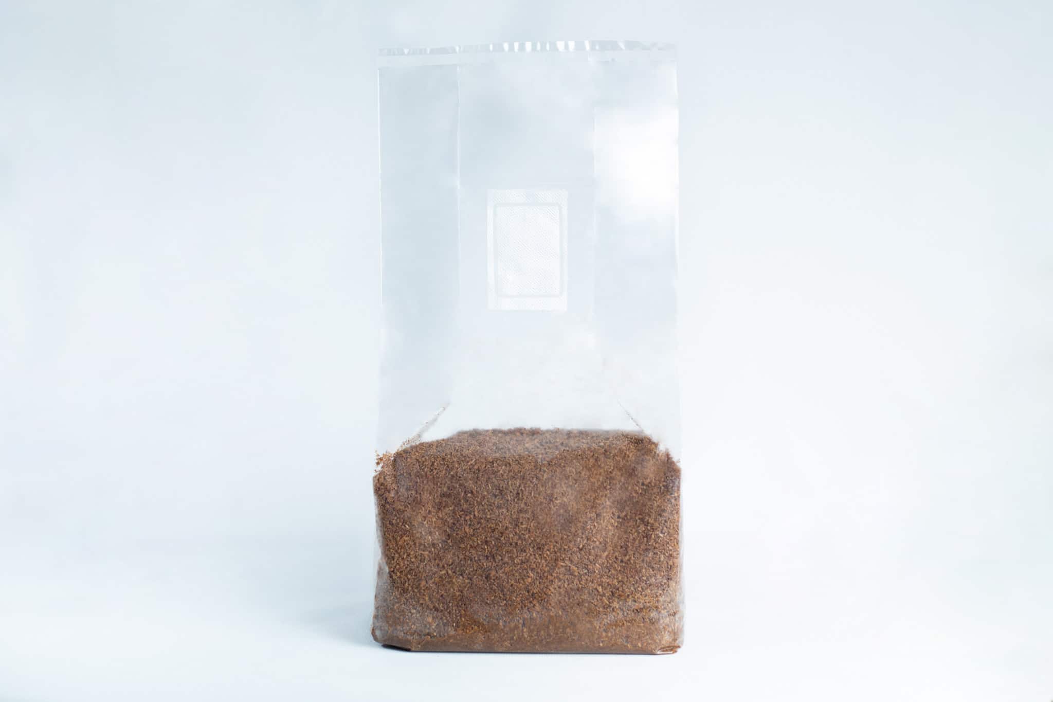 Monotub mushroom growing kit- Max Yield Bins 9 A clear plastic bag, filled halfway with brown granules of Masters Mix Mushroom Substrate Sawdust and Soya Pellets, is pictured against a white background.