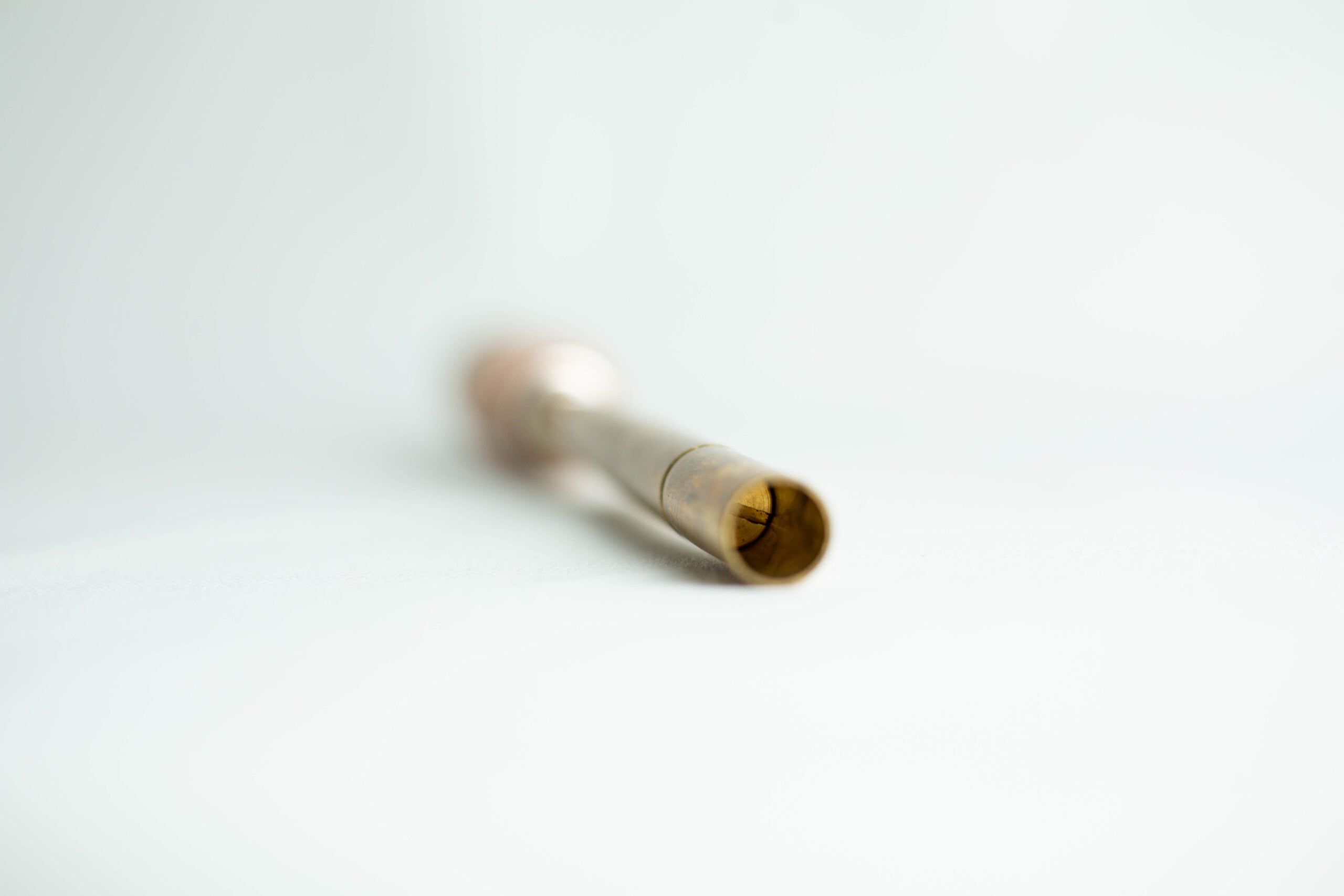 Sawdust Log Inoculation Tool for 12.5mm hole 3 A brass tube with a slightly flared end, lying on a white surface, focussed on the open tip.
