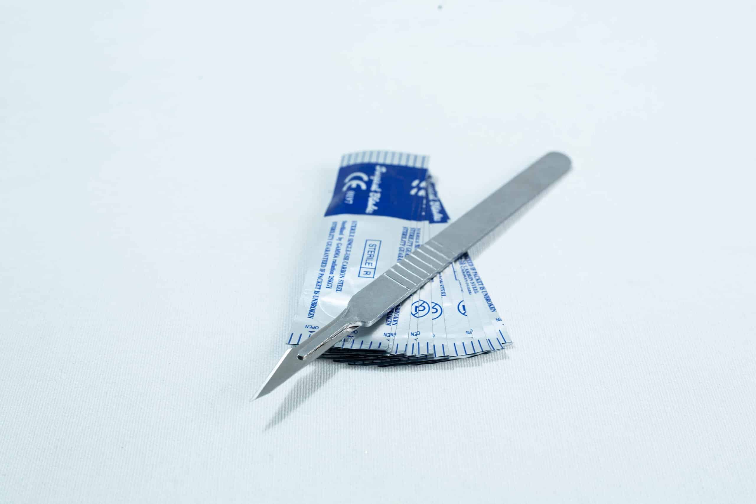 Scalpel handle #3 and blades #11 | Mycology 1 A metal scalpel rests on top of a blue and white sterile packaging on a white surface.