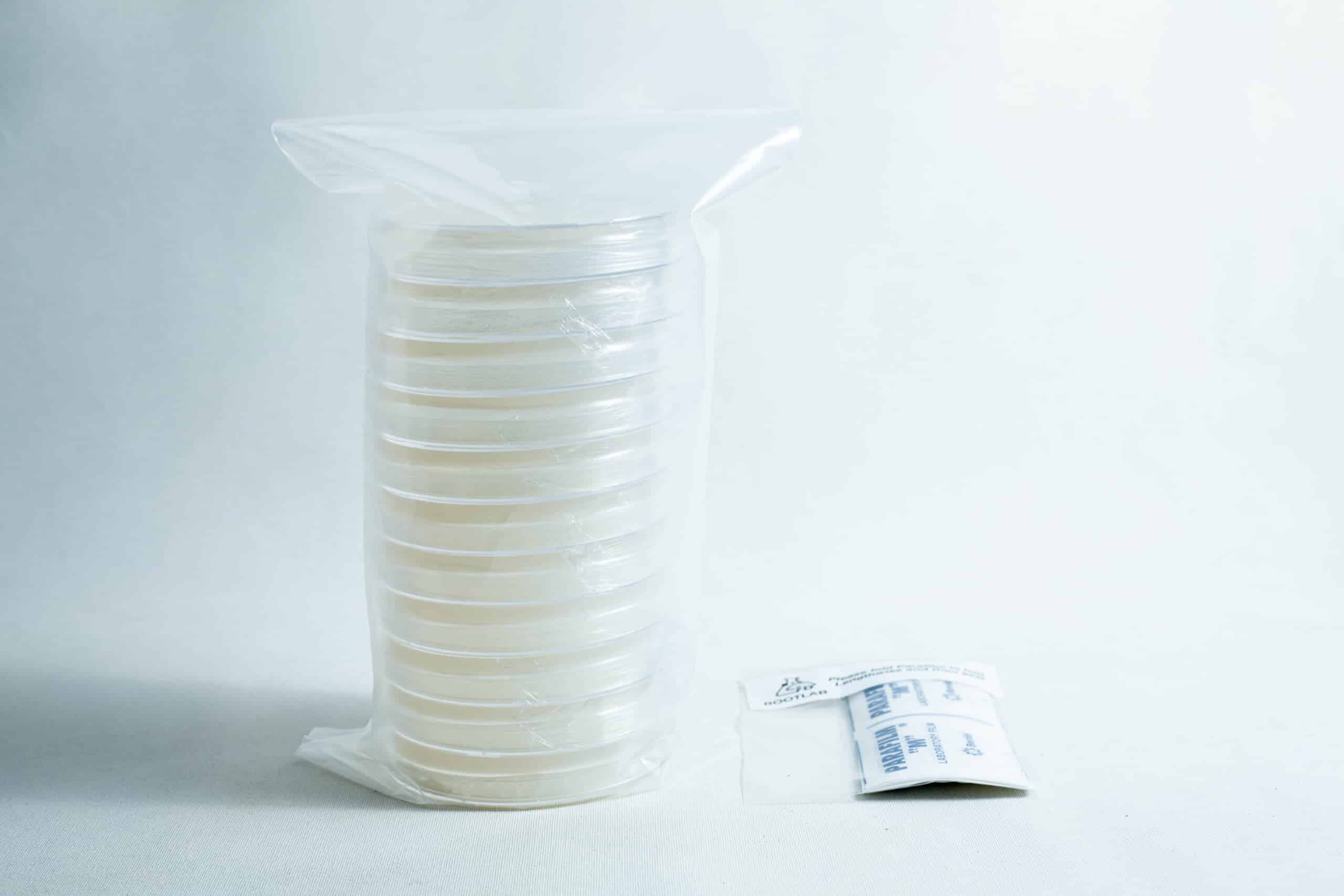 Sterile Water Agar Petri Dishes (WA) x10 with Parafilm 1 A stack of sealed petri dishes and a small packet on a white surface with a plain background.