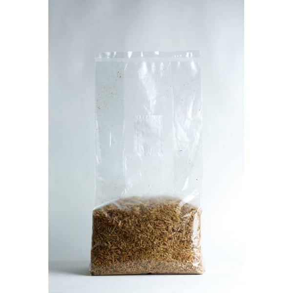 A clear plastic bag filled with brown woodchips against a plain white background.