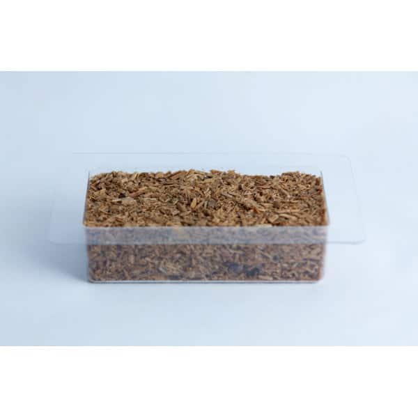 A clear plastic container filled with light brown wood chips on a white background.
