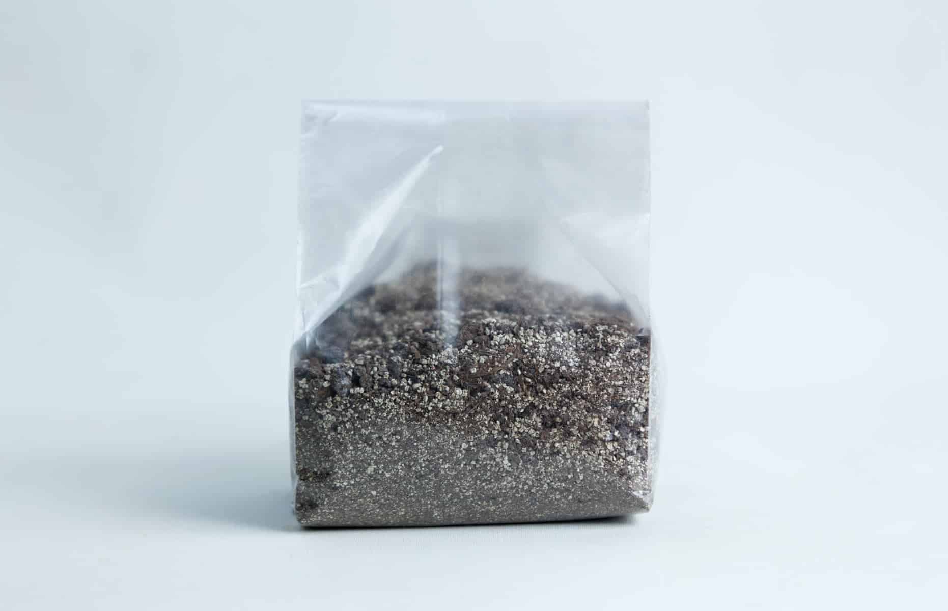 Monotub Mushroom Growing Kit-Premium 8 A clear plastic bag filled with a mixture of small, dark and light grains—perfect for use with the Monotub Mushroom Growing Kit-Premium—set against a plain background.