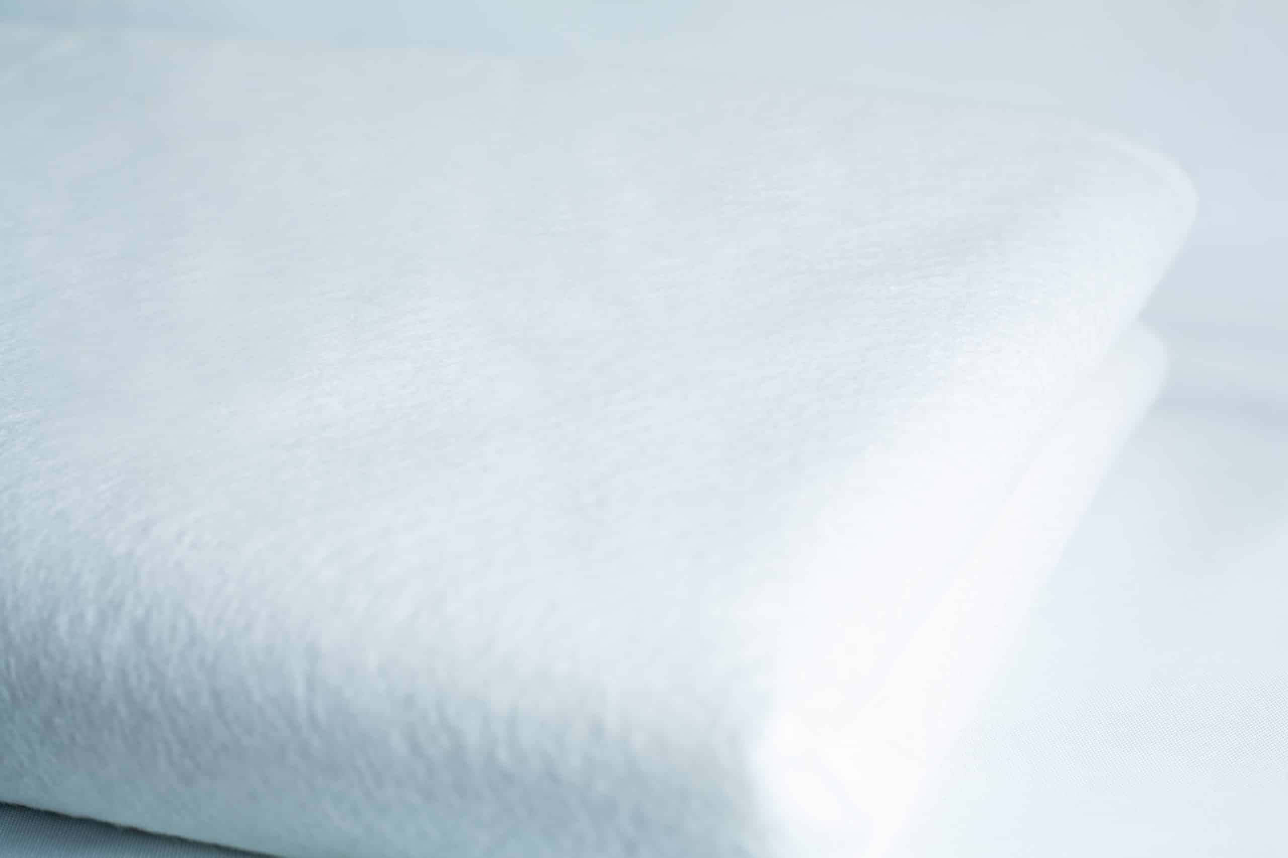 Light Log Blanket 3 A close-up of a neatly folded white towel and the Light Log Blanket displayed on a white surface.