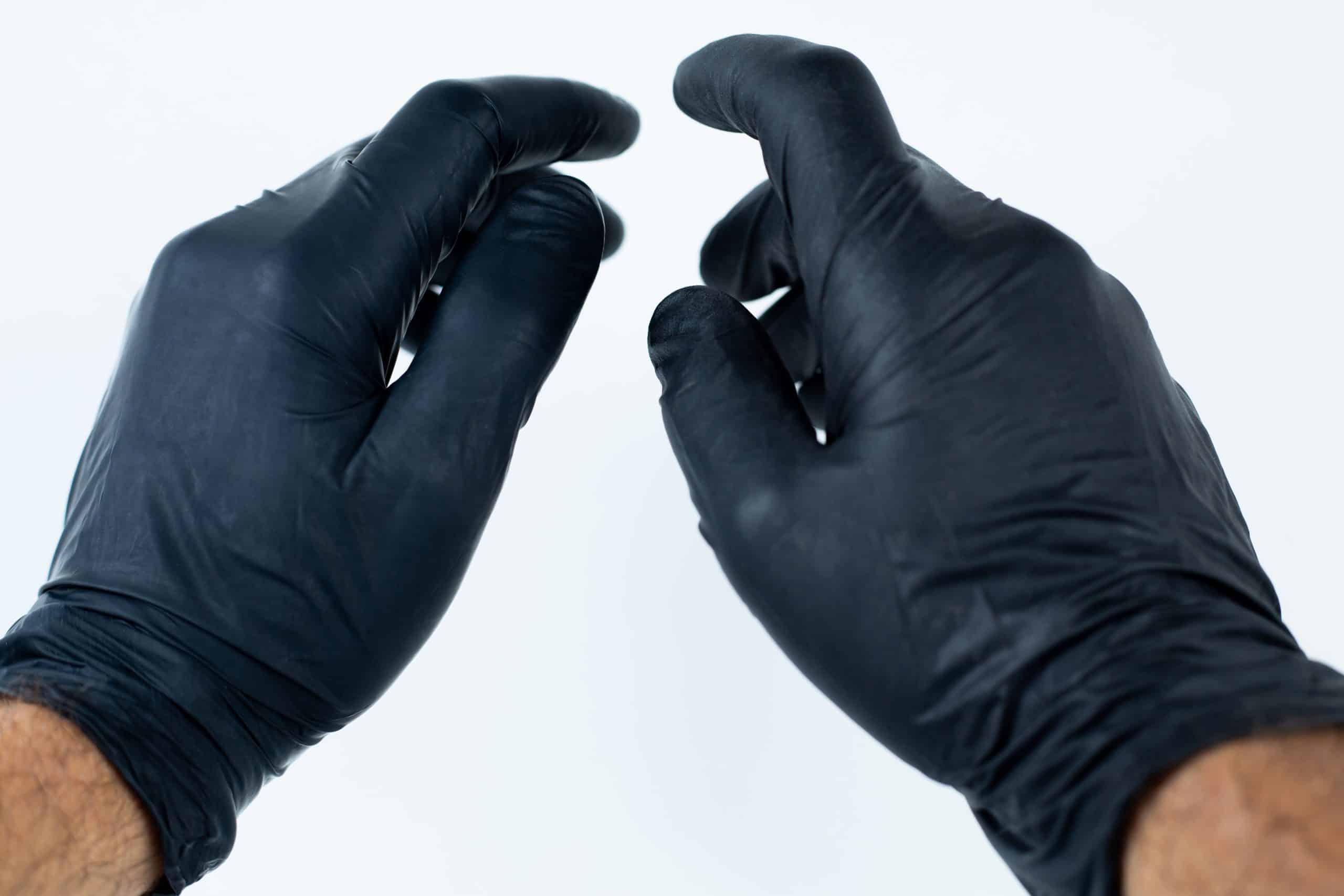 Nitrile Powder Free Disposable Gloves 1 Two hands wearing black disposable gloves are held up against a plain white background, suggesting readiness for hygienic tasks often paired with a Disposable Face Mask/Unit Individually wrapped.
