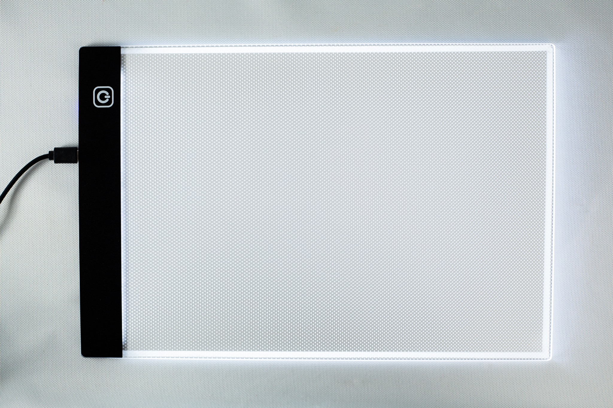 LED light Pad for agar 2 A rectangular LED light pad with a black edge and glowing white surface, plugged in on the left-hand side.