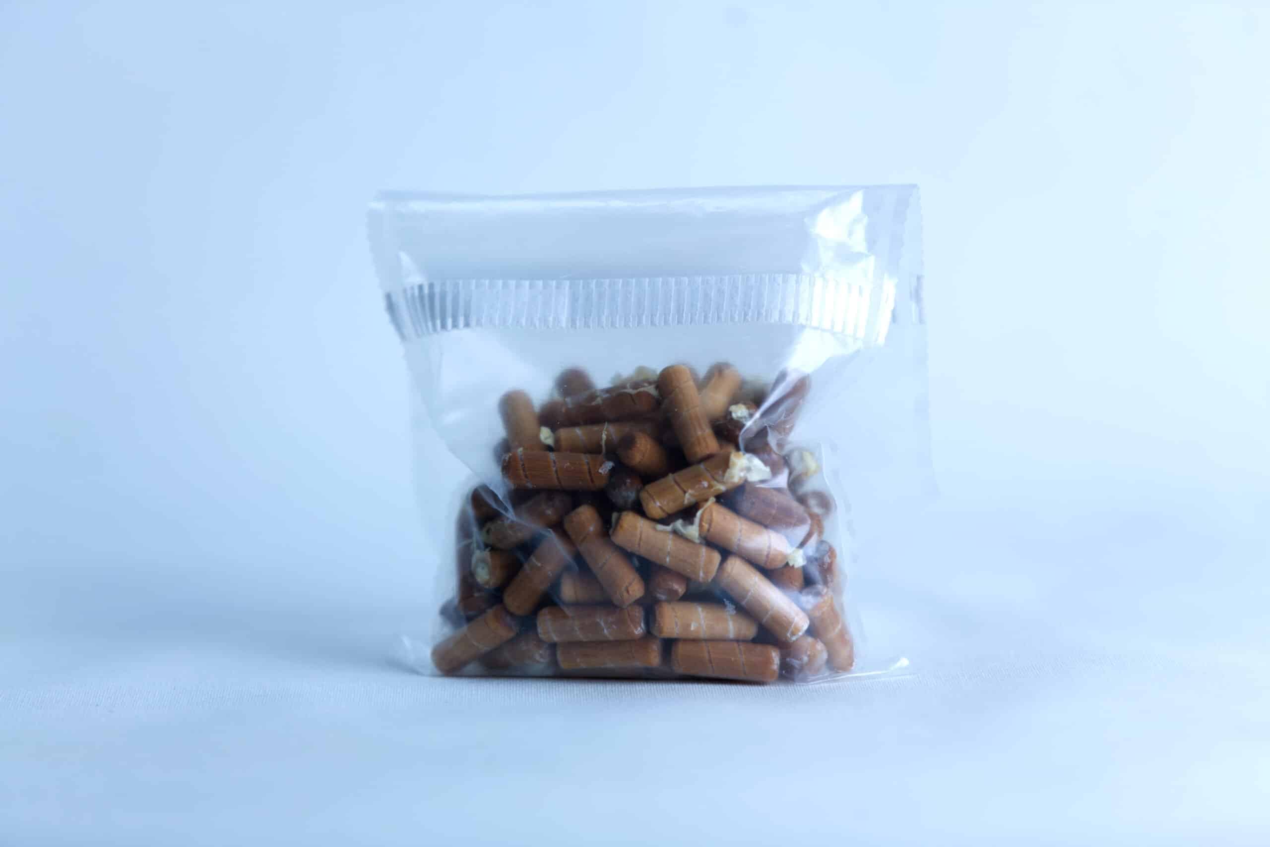 Log Dowel Mushroom Plug Spawn | Nameko | Pholiota microspora 3 Clear plastic bag containing Log Dowel Mushroom Plug Spawn for Yellow Oyster (Pleurotus citrinopileatus) is pictured against a light blue background.