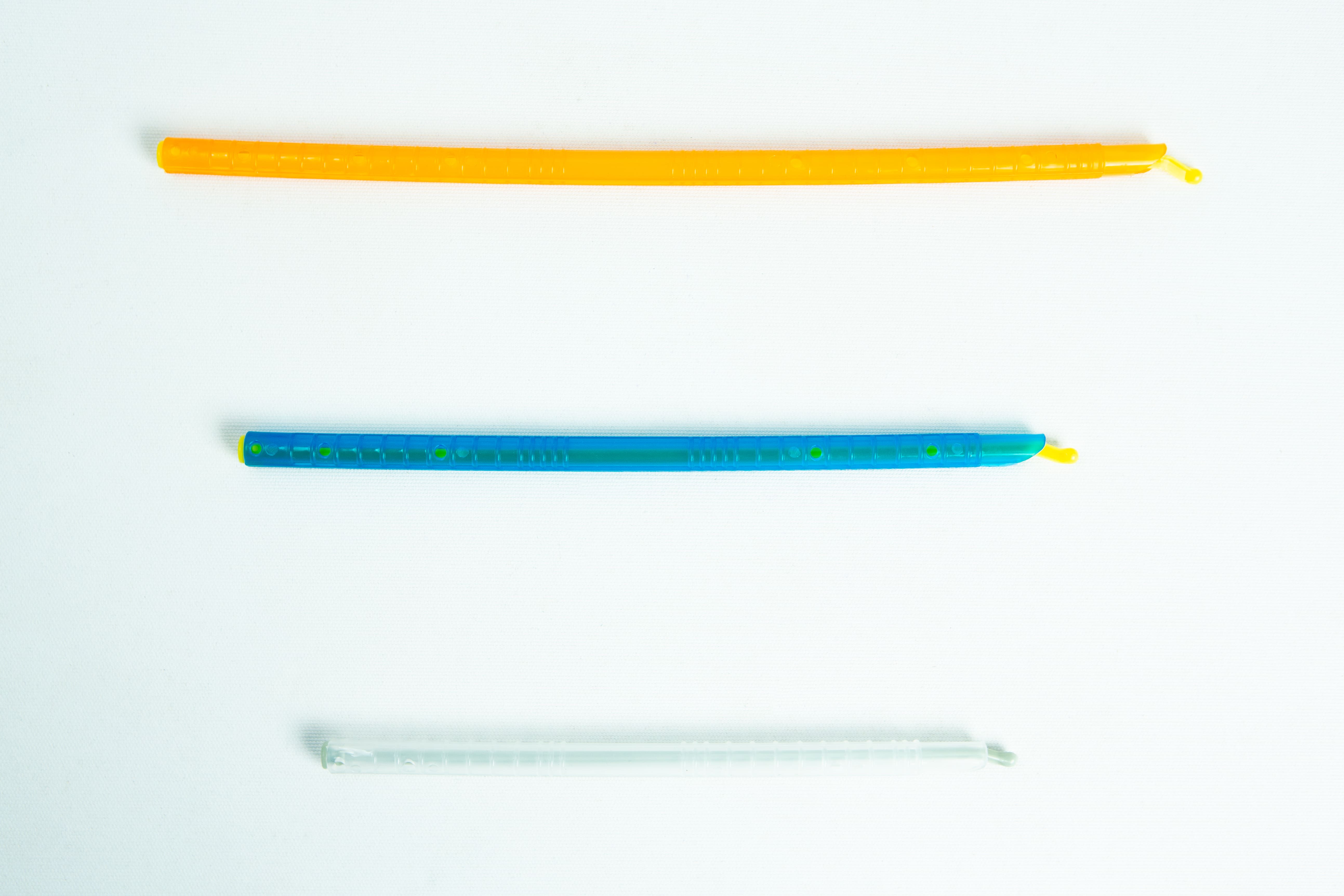 Mushroom bag sealing clip | Reusable 1 Three colourful twist ties, orange, blue, and clear, are laid out horizontally on a white background.