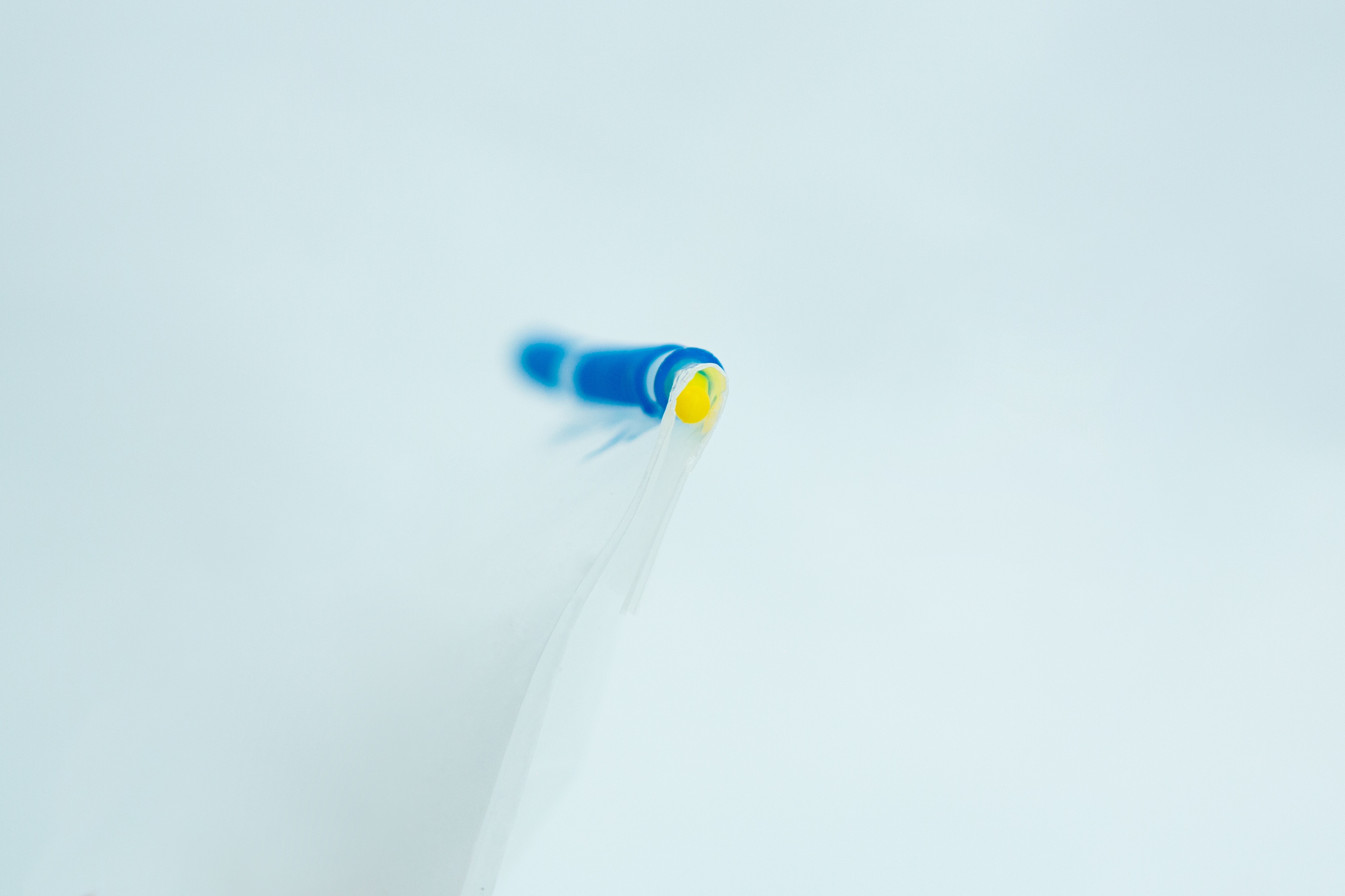 Mushroom bag sealing clip | Reusable 3 Close-up of a blue and yellow biro tip on a white background, with a shallow depth of field.