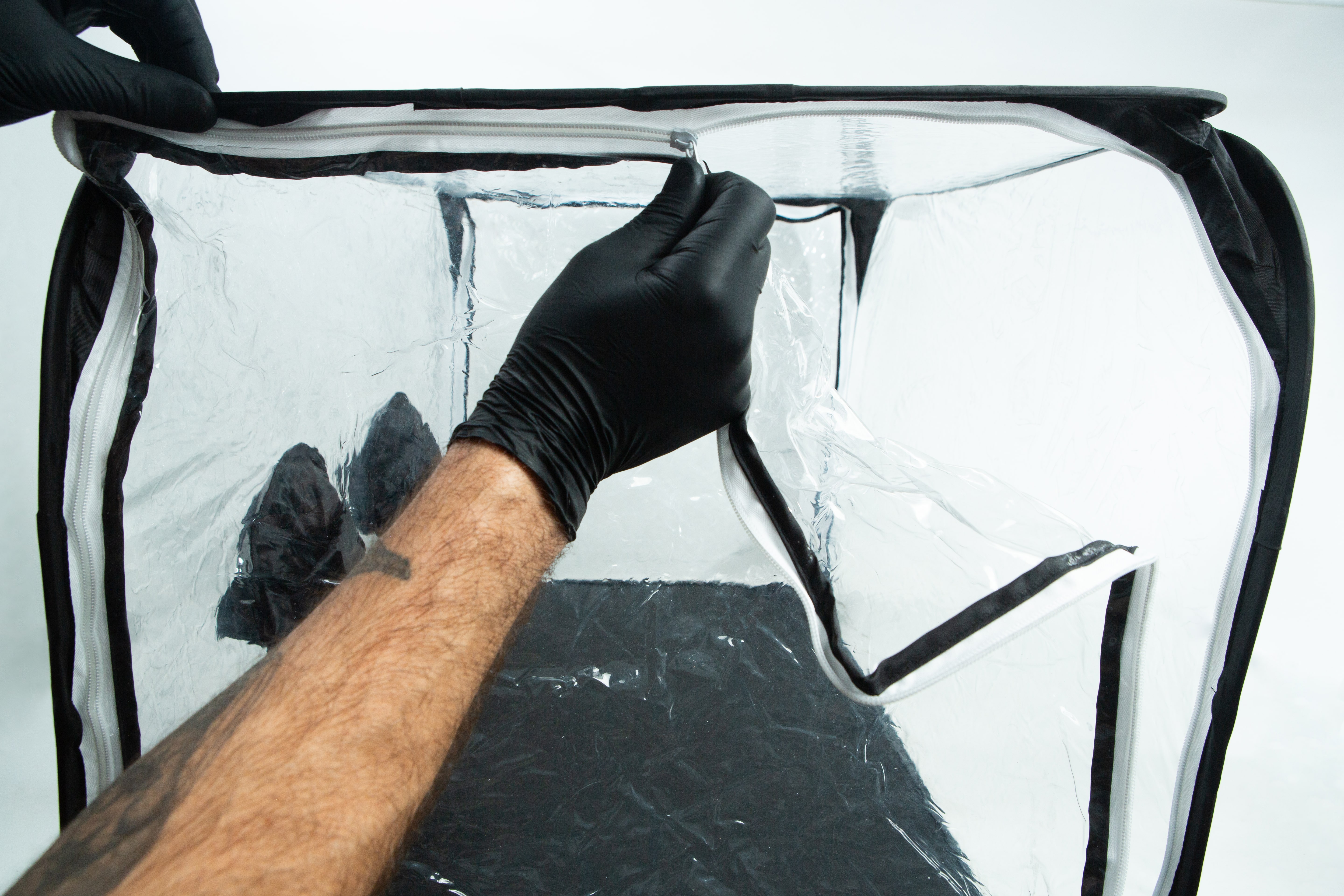 Still Air Box (SAB)| Mushroom | Large | Pop up 4 A person in black gloves unzipping a clear plastic enclosure with a black frame.