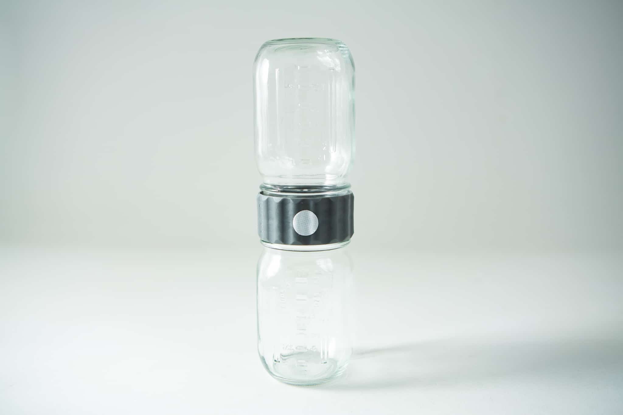 Plant Cell Biocoupler™ collar only (regular mouth) 7 The Plant Cell Biocoupler™ Glass Set (470ml, 355ml, 235ml) features two glass jars vertically joined at their openings with a metal connector, shown against a plain background.