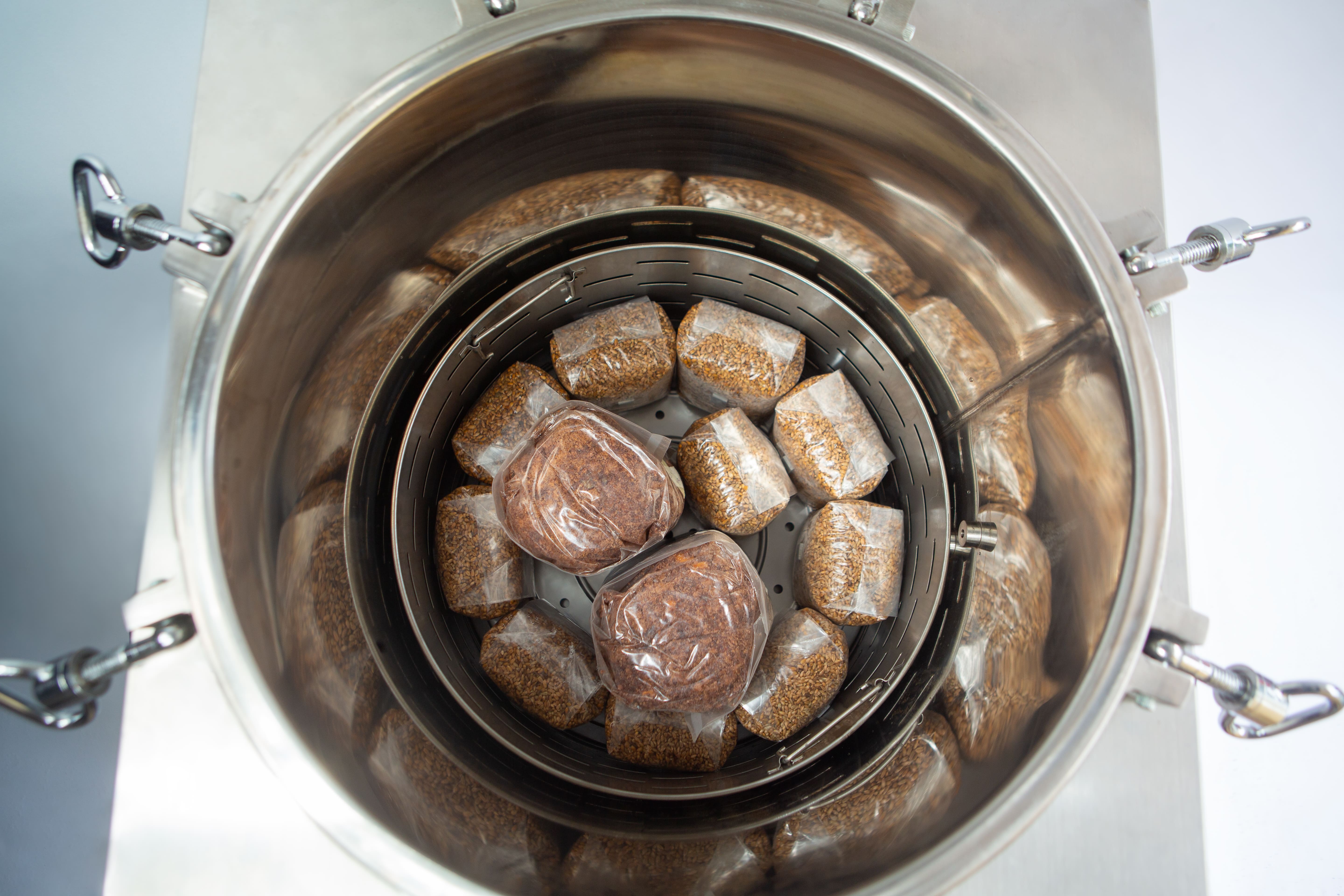 Vertical Autoclave 150 Liters (Automatic) | Commercial use | 6KW 12 Top view of plastic-wrapped food bundles arranged inside a stainless steel container.