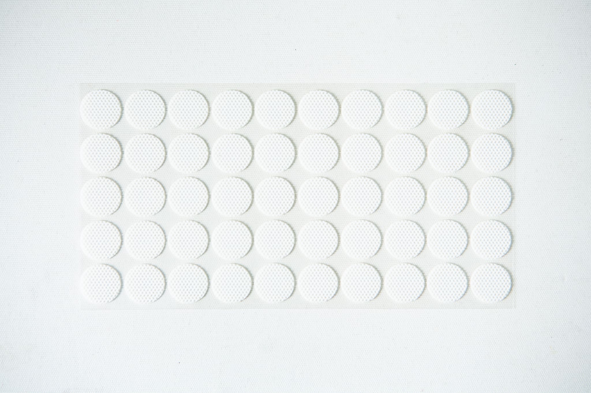 Self-healing injection port & Air Vent Filter-3M 11 A sheet of small, round, white adhesive stickers arranged in a grid pattern on a white background.