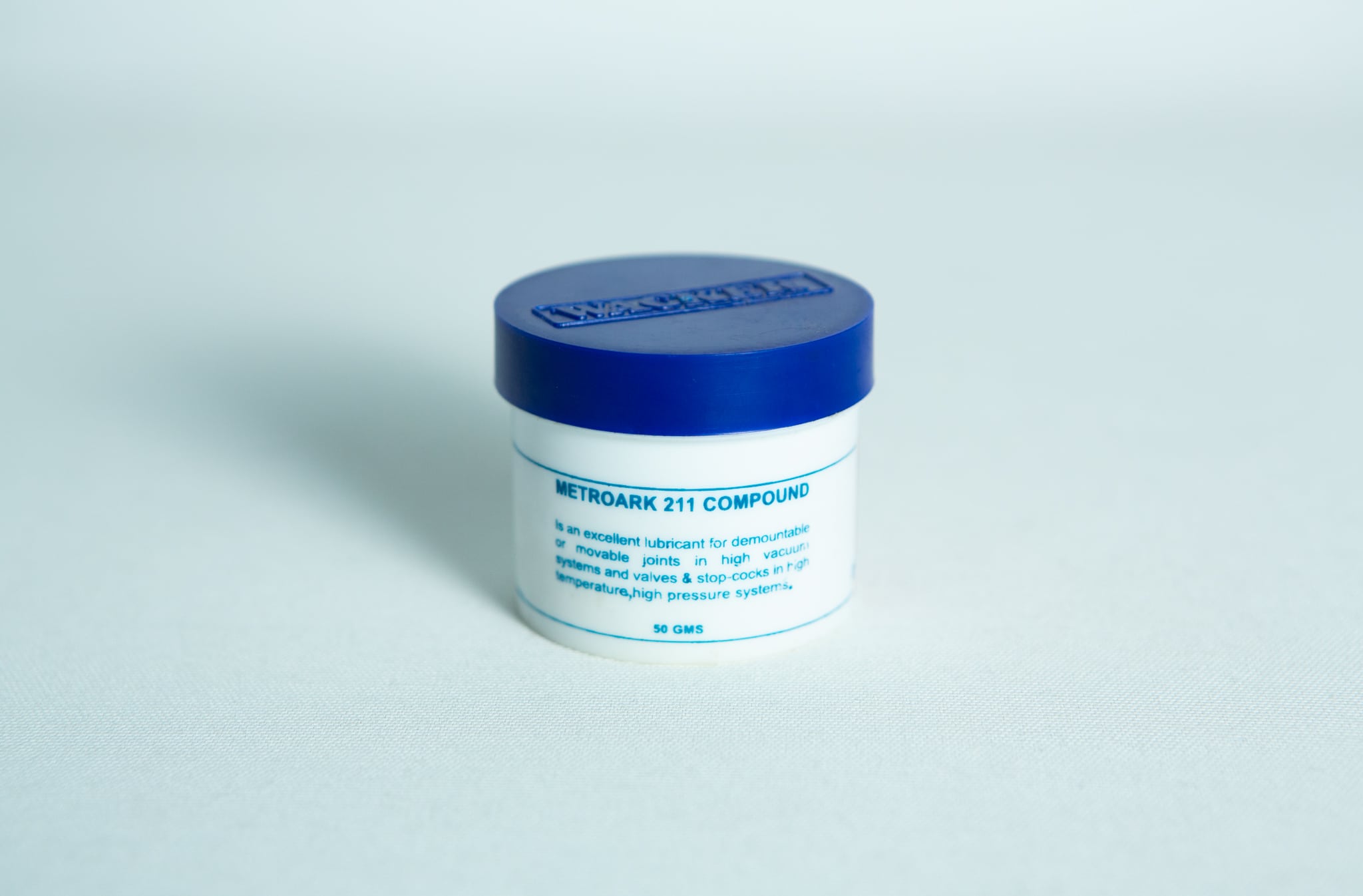 Silicone Grease Lubricant High Temp Vacuum - Metroark 1 White jar with blue lid labelled "Silicone Grease Lubricant High Temp Vacuum – Metroark," used as a lubricant for mechanical parts.