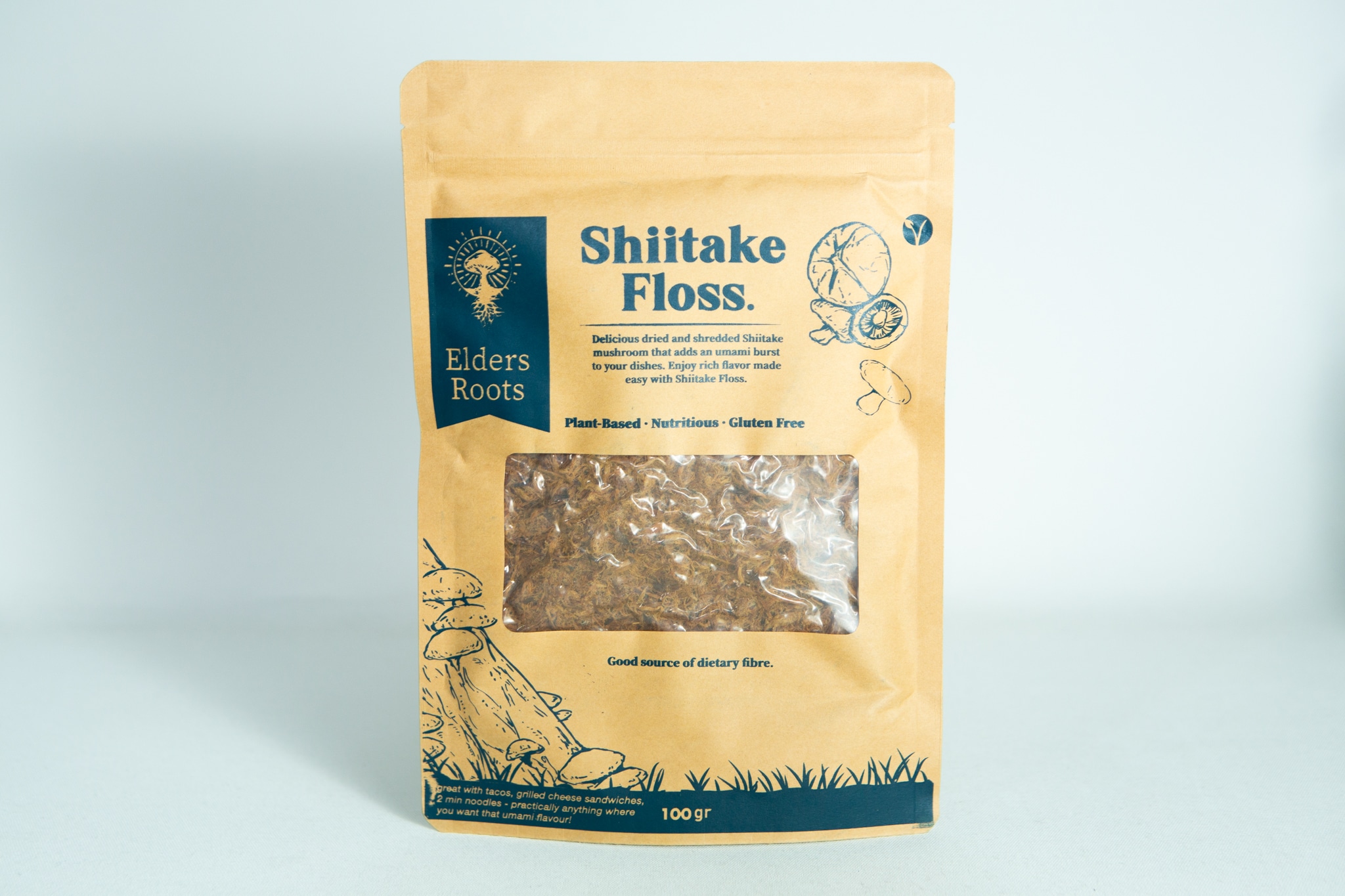 Shiitake Mushroom Floss | Vegan 1 A brown bag labelled "Shiitake Mushroom Floss | Vegan" with a clear window displays the shredded contents inside.